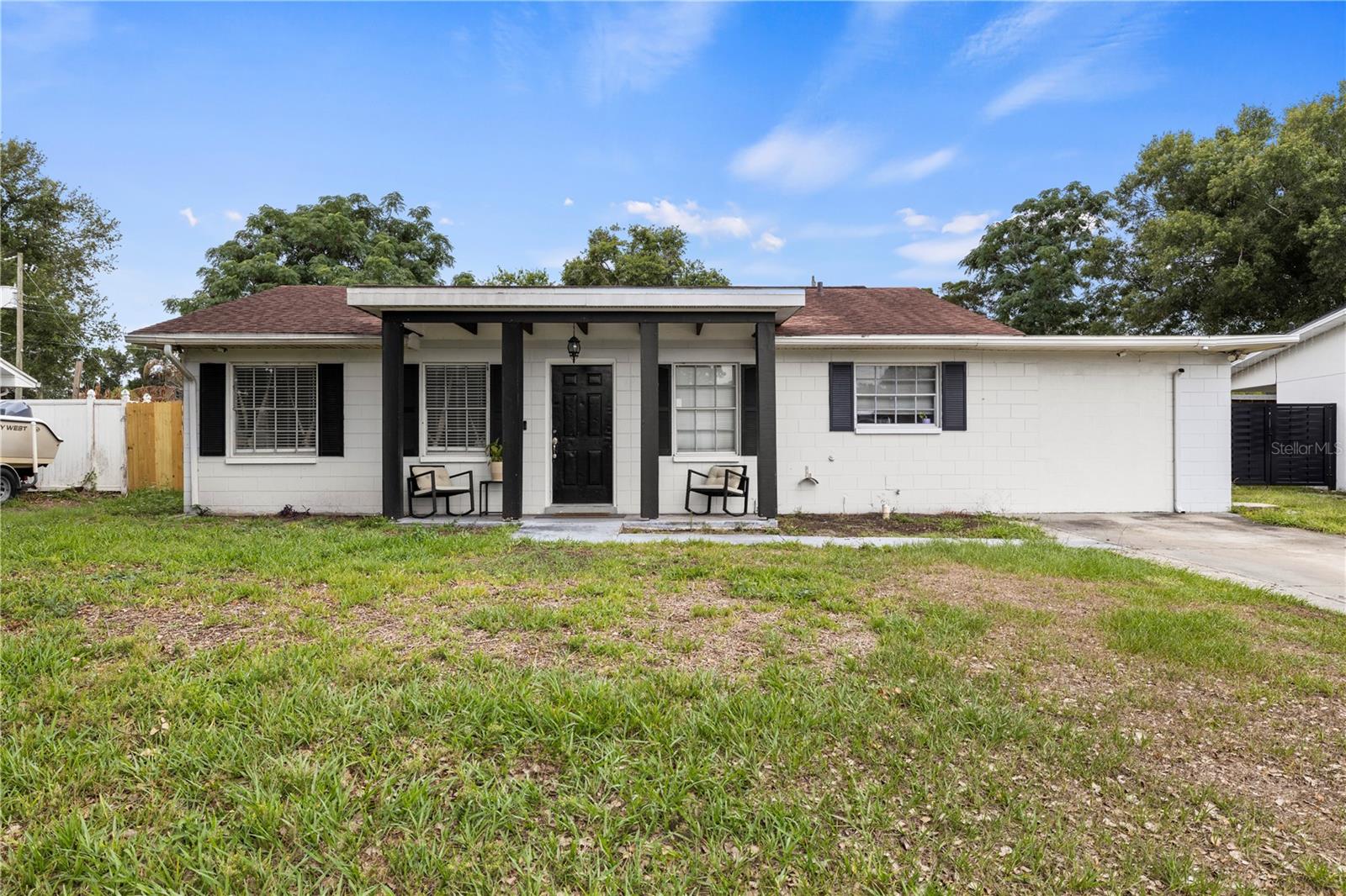 Tucked away in an area with no HOA, this 3-bedroom, 2-bath concrete block home in Lakeland checks a lot of boxes with 1,323 sqft. Fresh paint and laminate flooring run through the main living areas, with tile in the bedrooms and bathrooms, giving the home a clean, updated feel throughout.

The kitchen features white shaker cabinets, granite countertops, and stainless steel appliances. The primary bath is a standout — a walk-in tiled shower with a built-in bench and rainfall showerhead makes it feel more spa than starter. Out front, a covered porch with wood beam detail gives the home strong curb appeal.

The screened back porch is the kind of space you'll actually use — large enough for a dining set and seating area, with views of a fully fenced backyard. A metal carport on a concrete slab adds covered parking and storage, and with no HOA there's plenty of room for a boat, trailer, or extra vehicles.

Major systems are well maintained: roof (2017), air handler (2016), exterior AC unit (2021), septic serviced (2022). Close to shopping, dining, and parks in north Lakeland.