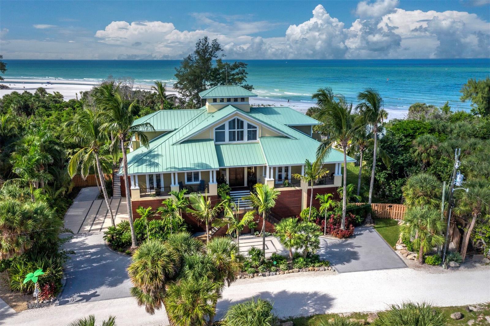 Welcome to this extraordinary Gulf-front estate located in one of Siesta Key’s most exclusive enclaves. Situated on a full acre in the private Sandy Hook community, this fully renovated, turnkey residence offers over 5,000 square feet of refined living space and more than 3,000 square feet of covered outdoor areas, all just a short stroll from Siesta Key Village and with direct access to a private community beach. Inside, the layout features five en-suite bedrooms, two powder baths, a dedicated office, and a three-car garage with beach cruisers and kayaks included. Floor-to-ceiling Andersen impact windows frame panoramic Gulf views, while rich finishes like Sapele mahogany siding, IPE hardwood decking, and a custom Pecky Cypress entertainment system reflect the home’s elevated craftsmanship. The chef’s kitchen is a showpiece, centered around a Labradorite Lumarian Blue granite island imported from Brazil, with Wolf, Miele, and Sub-Zero appliances throughout. The spa-inspired primary suite includes a waterfall feature wall, dual curbless shower, lighted soaking tub, and Toto smart toilets. A private elevator and full smart-home system ensure ease and efficiency. Outdoor living is exceptional, with a heated saltwater pool and Jacuzzi, a fully equipped summer kitchen, a covered outdoor living room with fireplace and TV, a poolside theater with dual fireplaces and TVs, and a sunset-facing gas fire pit. The professionally designed $1M+ tropical landscape includes advanced mosquito-misting and irrigation systems for effortless maintenance. With direct access to a private, resident-only beach and an ideal location just minutes from restaurants, shopping, and entertainment, this one-of-a-kind estate offers a rare opportunity to experience the best of coastal living on Siesta Key. Designed for elevated living and effortless enjoyment, 26 Sandy Hook Road S is more than a home—it is a fully realized Gulf-front sanctuary.