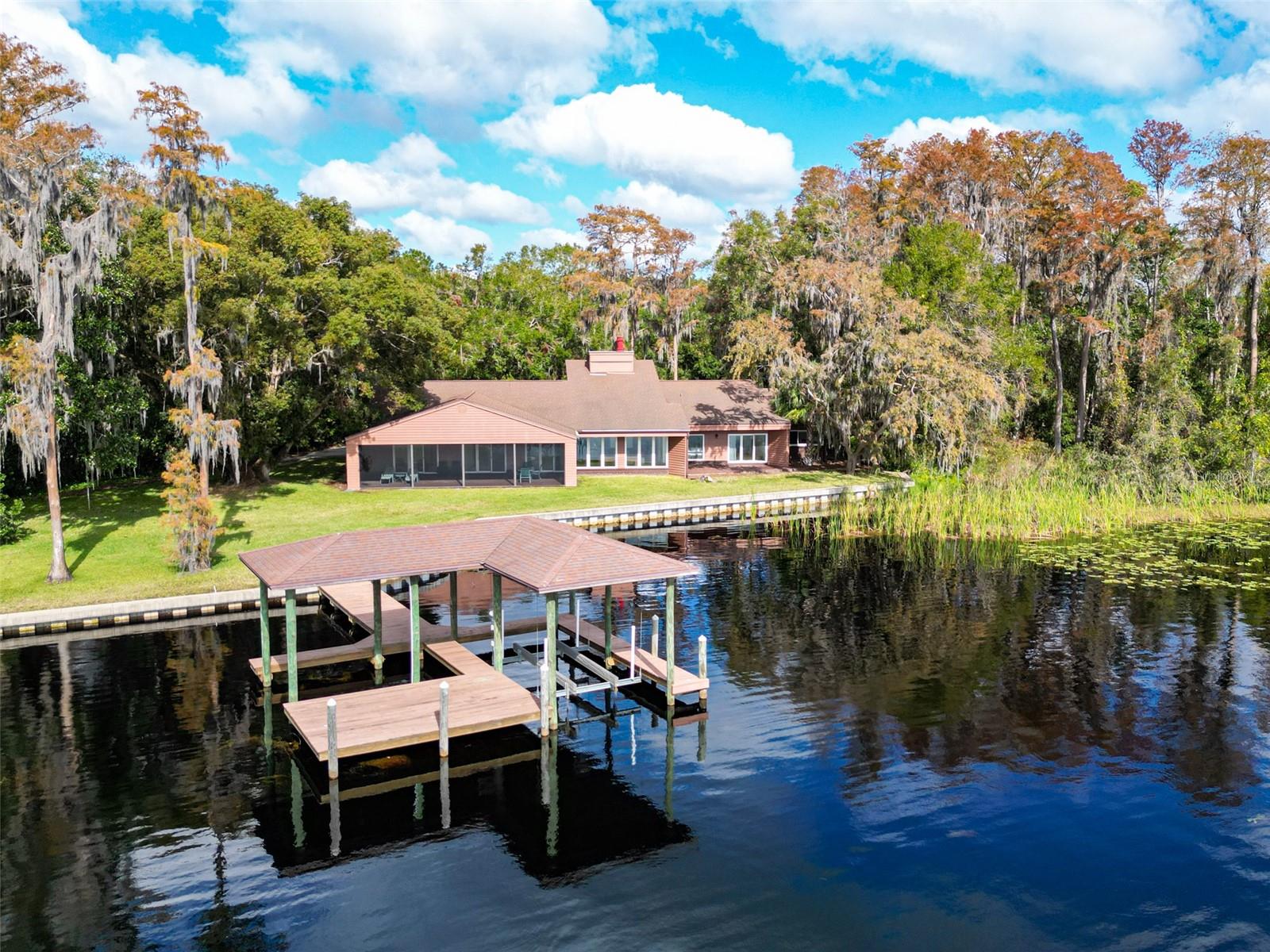 Discover the ultimate blend of luxury and tranquility in this stunning lakefront retreat on LAKE KEYSTONE, set on nearly two acres of secluded, meticulously landscaped property. Offering over 4,600 sq. ft. of living space, this estate is perfectly designed for those seeking privacy, breathtaking views, and unparalleled access to Florida’s premier lakefront lifestyle.

Arrive via a private drive that opens to a panoramic view of Lake Keystone, widely regarded as one of the most picturesque in the area. The property features a five-year-old concrete land retention wall and an upgraded dock equipped with a powered boat lift and additional electric capabilities, making it a boater’s dream. Whether launching from your PRIVATE BOAT RAMP or soaking in the natural beauty of the expansive backyard, this estate is your personal haven.

Inside, the home boasts a functional split-bedroom layout with 5 bedrooms, 3.5 baths, and an attached two-car garage. The lakeside design maximizes natural light, with oversized windows and sliding glass doors framing the serene water views throughout. The owner’s suite includes a dedicated office or sitting area, while the expansive secondary bedrooms and ample storage cater to both comfort and convenience.

For those with hobbies or a need for extra space, the detached workshop/garage can accommodate up to six vehicles, providing endless possibilities. Step out to the oversized covered lanai, the perfect spot to unwind while taking in the tranquil sights and sounds of the lake.

Located in the highly sought-after Steinbrenner School District, this exceptional home is just a short drive from Tampa’s finest dining, shopping, and entertainment. Don’t miss this rare opportunity to own a truly unique piece of lakefront paradise.