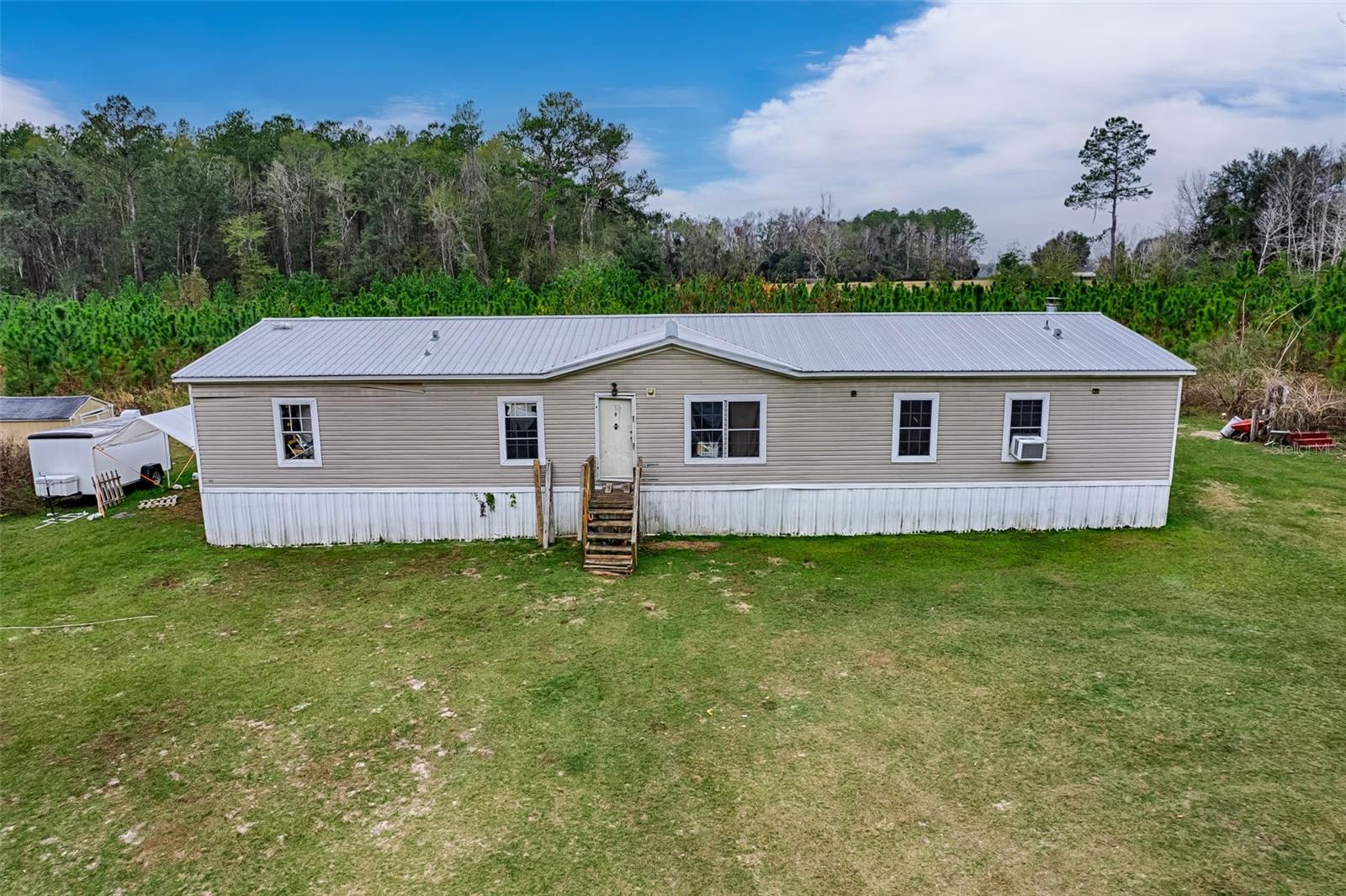 Discover the potential of this 4-bedroom, 3-bath mobile home set on a spacious 13.21-acre property, offering privacy, natural beauty, and opportunity. The land includes approximately 12 acres of timber, with 3 acres of newly planted pine, making it attractive for those interested in land value, future growth, or recreational use. A creek running through the property adds to the peaceful, natural setting.

The 2,280 square foot home is a fixer-upper, providing the chance to renovate and customize to your vision. The property is serviced by well and septic, offering flexibility and independence from municipal utilities. There is a 10x12 storage area on the property as well as an above-ground pool enhances the outdoor space and potential for entertaining.

With abundant acreage, mature and newly planted timber, and a scenic creek, this property is well-suited for investors, renovators, or buyers seeking a private rural retreat with long-term upside. Whether you’re looking for a renovation project, investment opportunity, or land with an existing residence, this property offers a rare combination of space and natural features.