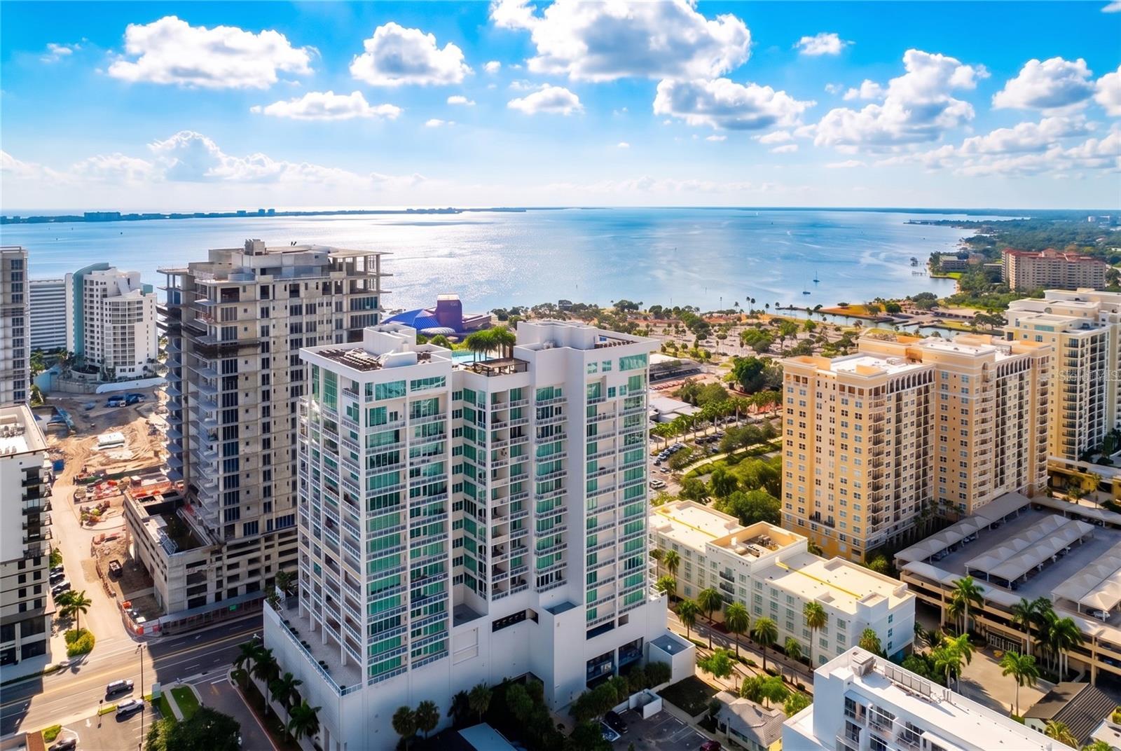 Unit 702 at BLVD Sarasota is a residence of scale, light, elegance, and quiet sophistication. With 3 bedrooms, 3.5 baths, and 3,962 sqft of interior living space, it offers the proportions of a true downtown home with the ease of elevated condominium living. Arrive by private elevator into a residence that feels expansive from the first moment, with warm wood floors, layered ceiling details, walls of glass, and beautifully framed views of Sarasota Bay, The Bay Park, the downtown skyline, and dramatic western sunsets.
The original floor plan was thoughtfully reimagined to create an enlarged living and media experience, giving the residence an uncommon sense of flow, flexibility, and ease. Formal dining, relaxed seating, kitchen, and media room live together naturally, with the media room set just beyond the main living area and framed by custom sliding glass doors, allowing the space to remain visually connected or quietly separate when desired. Three private balconies extend the living experience outdoors, including a generous terrace off the main living area, a private balcony off the primary suite, and an additional balcony off one of the guest suites.
At the heart of the residence, the kitchen brings together dramatic stone, generous cabinetry, an oversized gathering island, Sub-Zero refrigeration, Thermador appliances, gas cooking, wine refrigeration, and two walk-in pantries. Designed with both beauty and function in mind, the space feels equally suited for quiet mornings, effortless entertaining, and evenings that naturally gather around the island.
The primary suite continues the home’s sense of calm, with custom built-in closet space and a beautifully composed dual-sided bath connected by a shared spa-style shower. Two additional bedroom suites, each with its own ensuite bath, offer privacy and comfort for guests, family, or extended stays.
A built-in office and large laundry room support the practical side of daily living. Lutron motorized shades, ceiling speakers, and app-controlled smart-home features add comfort and ease throughout. Two assigned parking spaces and climate-controlled storage provide valuable everyday convenience.
BLVD Sarasota is one of downtown’s most private and amenity-rich addresses, with concierge service, rooftop pool and spa, fitness center, climate-controlled wine storage and tasting room, golf simulator, club room, conference room, pet amenities, and direct access to Sarasota’s arts district, Bay Park, the waterfront, restaurants, galleries, and the best of downtown living. The anticipated arrival of 1000 NORTH Sarasota, the members-only private club coming to BLVD this fall, adds yet another layer of distinction to this already exceptional downtown address.