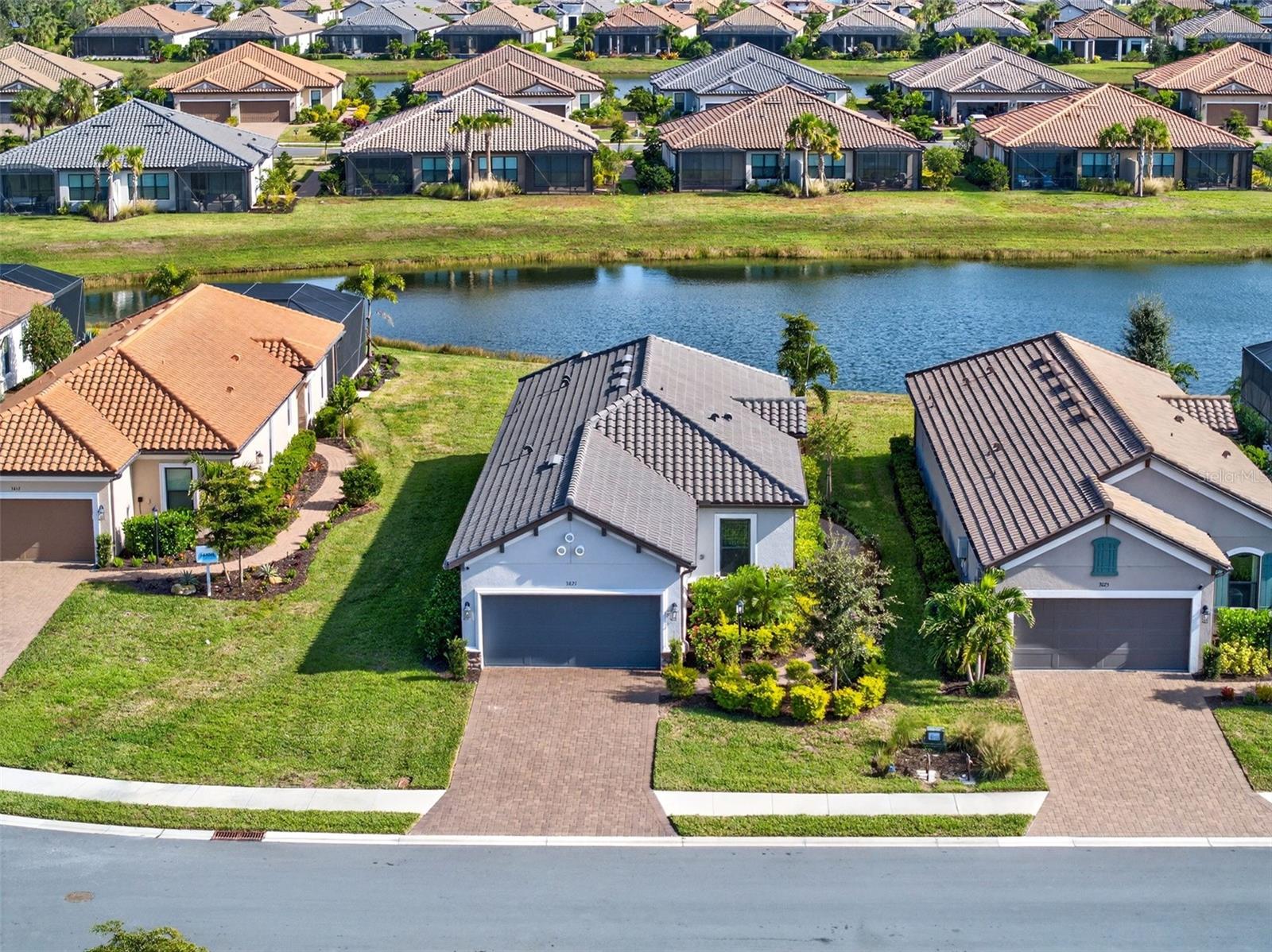 Experience effortless Florida living at 3021 Veneto Ct, a GOLF DEEDED, move-in-ready residence set on a peaceful lakefront homesite within the sought-after Esplanade at Azario. Positioned near the end of a quiet cul-de-sac, this home offers a serene setting where water views, open skies, and low-maintenance living create a true sense of escape.

Designed for both comfort and convenience, the home welcomes you with an elongated driveway and garage extension, enhanced by epoxy-coated garage flooring for durability and a polished finish. Both the driveway and lanai have been professionally sealed, adding long-term protection and a clean, well-maintained appearance. Best of all, this is a maintenance-free, resort-style community, where lawn care and exterior maintenance are handled for you—allowing more time to enjoy the lifestyle you moved here for.

Inside, light-filled living spaces showcase neutral tile flooring throughout the main areas, tray ceilings, recessed lighting, and a soft, coastal-inspired color palette. The open-concept design flows effortlessly, making everyday living and entertaining feel seamless. The kitchen is both stylish and functional, featuring quartz countertops, stainless steel appliances, ample cabinetry, and a timeless tile backsplash, all overlooking the dining and living areas.

Sliding glass doors open to an extended screened-in lanai, where tranquil lake views create a private outdoor retreat. The outdoor living space is pre-plumbed for an outdoor kitchen, offering endless possibilities for alfresco dining, sunset gatherings, or quiet mornings overlooking the water.

The split-bedroom layout provides privacy and versatility. The primary suite is a peaceful sanctuary with tray ceiling detail, abundant natural light, plush carpeting, and a spa-inspired ensuite with dual vanities, a walk-in shower, and a generous walk-in closet. A guest bedroom, full bath, and flexible den offer space for visitors, a home office, or a cozy media or reading room. A thoughtfully designed laundry room with custom cabinetry and utility sink adds everyday practicality.

Life at Esplanade at Azario extends well beyond your front door. Residents enjoy championship golf, a resort-style pool, full-service spa, fitness and yoga studios, pickleball and tennis courts, and a vibrant social calendar. Dining experiences, wine tastings, cooking classes, and a casual on-site pizzeria complete the resort atmosphere—all set within the heart of Lakewood Ranch.

This is more than a home—it’s a lock-and-leave lifestyle designed for relaxation, connection, and enjoying every moment of coastal Florida living.