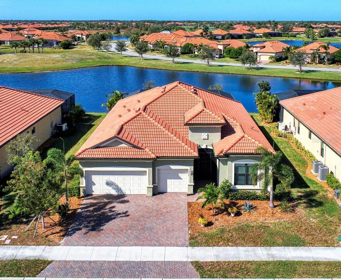A MUST SEE GEM: 2021 STUNNING SUMMERVILLE II OPEN CONCEPT 3BR, 3BA PLUS DEN, POOL HOME WITH 3 CAR GARAGE AND SPECTACULAR LAKE VIEWS IN THE GATED, AMENITY RICH, GOLF COMMUNITY OF SARASOTA NATIONAL. The HOA fee includes two golf memberships, with no extra buy-in fees. Discover the epitome of luxury living in this coveted, idyllic, resort lifestyle community. Amenities include a 30,000 sq ft club house with a massive resort style pool & spa, three on site restaurants, 18 hole championship golf course, day spa, coffee house, library, playground, dog park, card room, pickle ball/tennis/bocce ball courts, event lawn and 7,000 sq ft fitness center with top of the line equipment, personal trainers and fitness classes. The lush sprawling grounds of Sarasota National, a 2400-acre Audubon Bird Sanctuary, are perfect for biking, golfing, walking or running. This rarely available 2440 sq ft Summerville II floor plan, brilliantly designed for everyday living as well as entertaining, is sure to impress the most discerning buyer. With designer features and a neutral color palette, it exudes warmth and sophistication. Notable features of this home include hurricane impact windows, 10ft ceilings, 8 ft doors, French doors, tile flooring throughout, crown molding and tray ceilings. The custom oversized kitchen is a Chef's dream with an enormous granite island, a Fulgor Milano gas range with oven, a second wall oven and microwave, wine refrigerator, wine racks, a farmhouse single basin oversized sink, undercabinet lighting, pull out drawers, designer tile backsplash, walk in pantry and GE Profile stainless steel appliances. The luxurious expansive owners suite includes sliders to the covered lanai & pool/spa, a tray ceiling and crown molding. The en-suite bathroom boasts 2 oversized custom walk in closets with ample storage, 2 separate sink areas, crown molding and an enormous tile shower. The split floor plan has 2 additional bedrooms, one with an en-suite bathroom. The den/office has custom built in shelving, storage and a desk and can quite easily serve as a forth bedroom. The spacious west facing screened in outdoor oasis is made for entertaining and enjoying the Florida lifestyle and spectacular sunsets. This area features a 15 x 27 ft heated pool, spa with a waterfall feature, custom lighting, custom built petrified wood cabinetry, under counter beverage refrigerator and a motorized retractable awning. The front porch entry is screened to allow for a refreshing cross breeze through the impressive double entry doors. The oversized 3 car garage with epoxy flooring contains an abundance of built in storage for your extra toys.  The laundry room, located just off of the garage, also has ample cabinets for storage. This home is just minutes away from Downtown Wellen Park, where you can enjoy local restaurants, shopping, farmer's market, outdoor concerts, a gorgeous 80 acre lake or take in a baseball game at the Atlanta Braves spring training facility. Three beautiful beaches and historic downtown Venice are less than 15 minutes away. Don't miss out on this gem in one of most beautiful, highly sought after communities in Venice.  Schedule your private showing today!