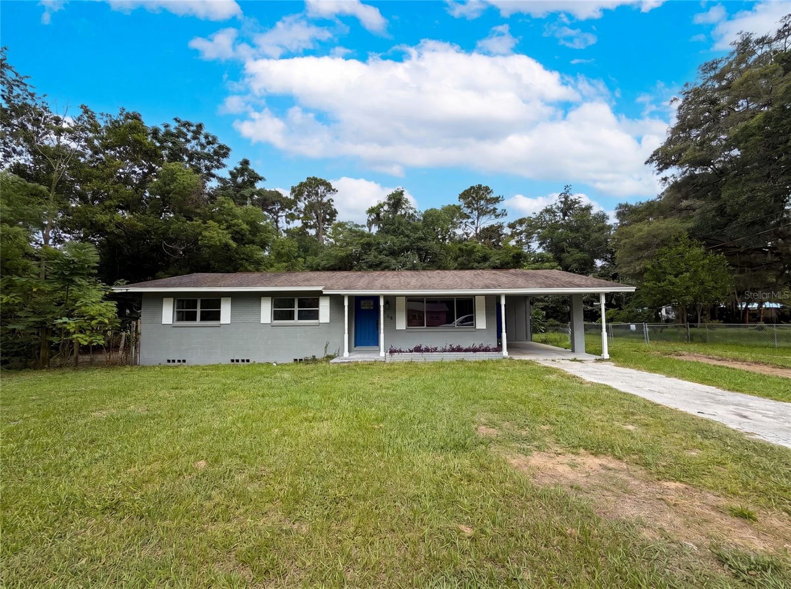 Virtually Staged. Set on a large lot of over a third of an acre, this single-story Ocala home offers easy one-level living and plenty of room to spread out. The interior has been refreshed with fresh paint and updated luxury vinyl plank flooring, centered on a bright, reworked kitchen featuring crisp cabinetry, stylish dark countertops, a new range, and a sunny window over the sink. Comfortable living and dining areas flow together for everyday ease, while three bedrooms and two full baths keep things practical and low-maintenance. A standout enclosed Florida room adds flexible bonus space for an office, playroom, or lounge, opening to a screened porch and a sprawling, fully fenced backyard shaded by mature trees. A covered carport and extended driveway provide convenient parking, leaving the expansive grounds free for gardening, entertaining, or simply enjoying the outdoors. Ideally located near shopping, dining, parks, and downtown Ocala, this move-in ready property is a rare find.. Included 100-Day Home Warranty with buyer activation