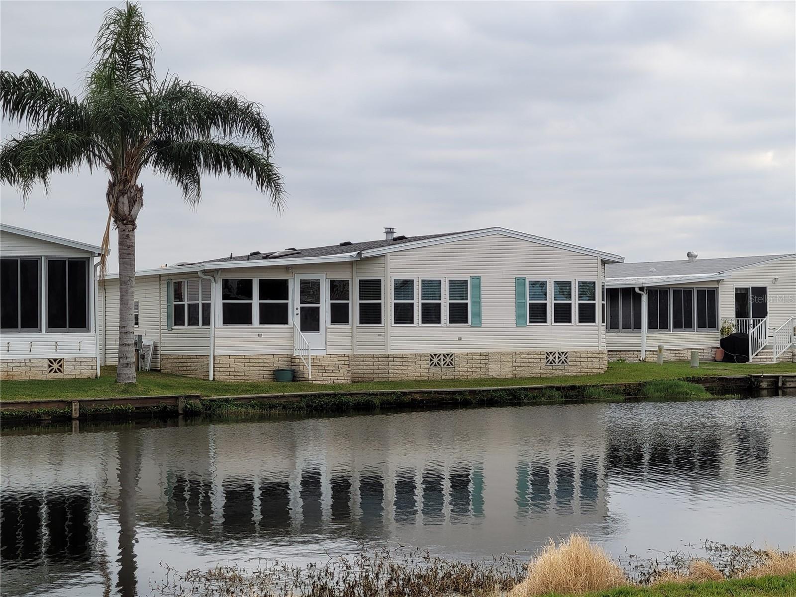 An amazing 1993 manufactured home on you own land! Water view as this home is on the pond. 1910 sq footage provides spacious rooms. There is a new Architectural Shingle roof that has "Cool Roof Technology" and a transferable warranty, New carport, New Windows, Insulated panels and door on Florida Room,  A formal DR / LR combo as you enter. The master suite takes the full width of the home! Deep closets, en-suite bathroom. The joy of this house is the 2020 updated Kitchen, with granite counter tops, breakfast bar, eating area, and the family room that enjoys the open concept with the kitchen. The view is delightful and available from all across the back of the house. There is a Florida Room off the kitchen (on AC system) that leads outside. Laminated Flooring, freshly painted, and totally updated! Unfurnished and no golf cart included. Enjoy 18 holes of golf for just $3 green fees in this Gated, Golf Community, located just outside of the city, and approx. 1.25 hr from either coast. Great access to Disney, Legoland, and BOK Tower, just to name a few local attractions. A Community where you enjoy $3.00 Green Fees as part of your HOA dues! In this very friendly, resident-owned community, you can be as active or inactive as you choose! Gatherings at the private Pub or the Community Room, fishing on Lake Henry, gardening, tennis, golf, shuffle board, pickelball, horseshoes, swimming in the heated pool, enjoy the hot tub or the workout room! Contact agent for this community's website address and documents, including Rules/Regs, Application, Financial, and Bylaws. HOA INCLUDES A DVR PLUS 2 HD CABLE BOXES AND INTERNET! (Minimum age in this 55+ community is 50 years old)