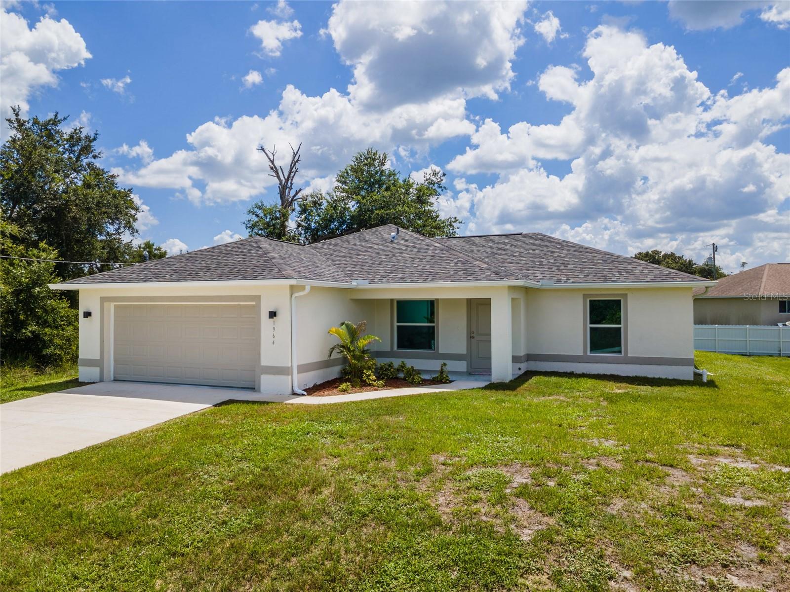 Virtually Staged. Welcome to modern Florida living in the desirable Greenbriar area of Lehigh Acres. This beautifully crafted new construction home offers over 1,500 square feet of thoughtfully designed living space, featuring 3 bedrooms, 2 bathrooms, and a highly sought-after split-bedroom floor plan that perfectly balances privacy and functionality. Step inside to discover an open-concept layout enhanced by elegant tile flooring throughout, tray ceilings, and an abundance of natural light. The spacious living, dining, and kitchen areas seamlessly flow together, creating the ideal setting for both everyday living and entertaining. At the heart of the home, the chef-inspired kitchen showcases quartz countertops, soft-close cabinetry, a stylish tile backsplash, ample storage space, and modern finishes designed to impress. The oversized laundry room and abundant storage throughout the home provide both convenience and practicality. The private primary suite offers a relaxing retreat, while the generously sized guest bedrooms feature large closets rarely found in homes of this size. An epoxy-coated two-car garage adds durability and a polished finish to the home's impressive list of upgrades. Enjoy Florida's year-round outdoor lifestyle from both the welcoming front patio and the spacious rear patio overlooking the fully fenced backyard. A vacant lot to the left of the property provides additional privacy and open space, enhancing the home's peaceful setting. Combining quality craftsmanship, upscale finishes, and a desirable location, this move-in-ready new construction home delivers exceptional value and modern comfort in one of Lehigh Acres' growing neighborhoods.