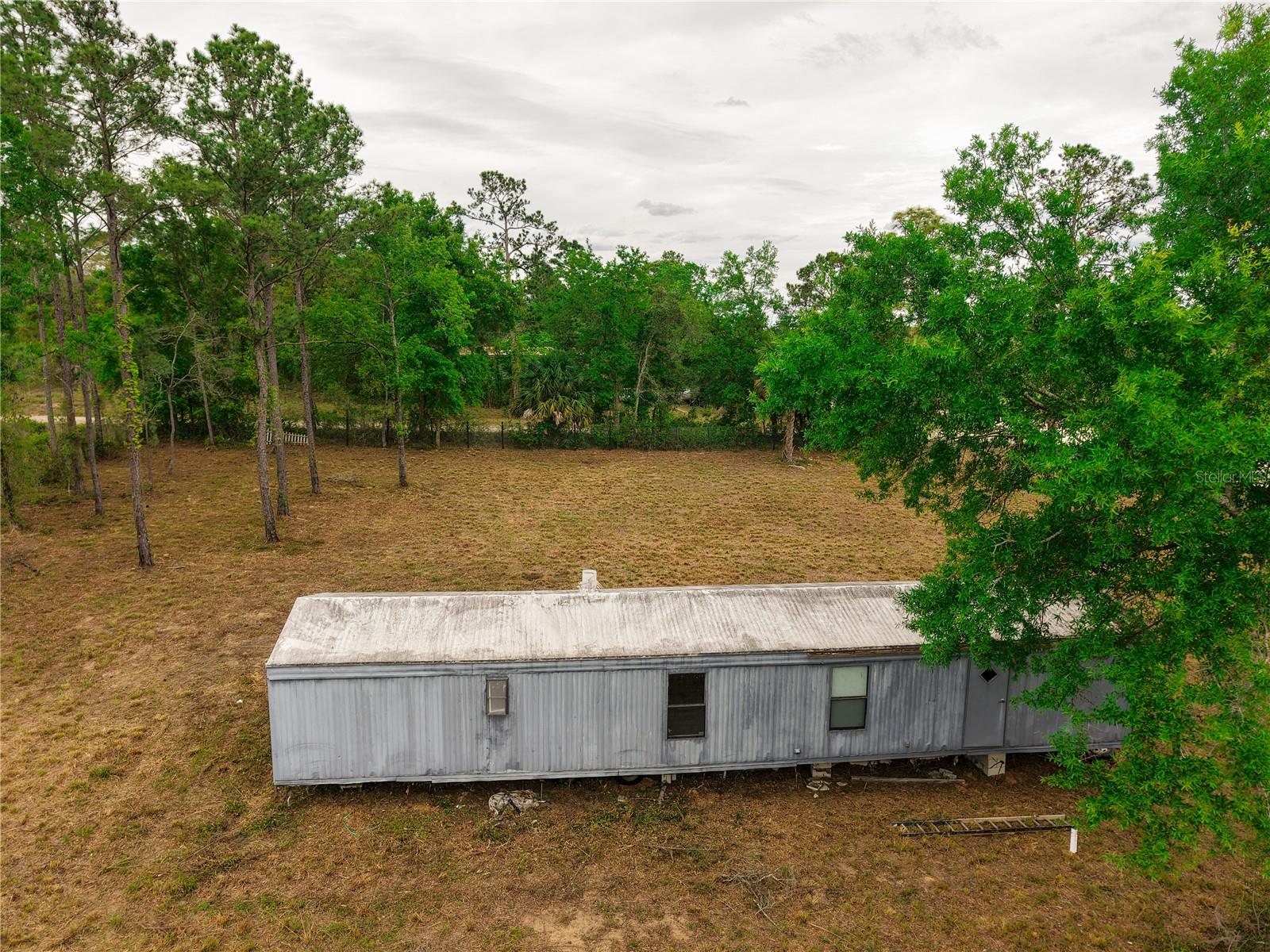 CASH ONLY. Welcome to your slice of country paradise in beautiful Williston, Florida! Nestled on a serene and private 1-acre corner lot zoned Agricultural, this property is perfect for those seeking space, flexibility, and a relaxed rural lifestyle. Property features a new well and septic. A survey and plans are available upon request .This lot is fully fenced and cleared. Whether you're searching for a peaceful primary residence, a weekend retreat, or a smart investment opportunity, this property offers incredible potential with room to grow.  Newer manufactured homes on 1-acre lots in the area are selling between $252,000 and $300,000, making this an excellent opportunity with strong upside potential. Act before it's too late.  Enjoy peaceful outdoor living with NO HOA, surrounded by nature, with ample space to create your dream garden, add outbuildings, or start your own hobby farm. With flexible Agricultural zoning, you can bring your chickens, goats, etc. Conveniently located just minutes from downtown Williston.  Outdoor enthusiasts will love the proximity to nearby springs, state parks, and scenic equestrian trails, making this an ideal setting for those who enjoy Florida’s natural beauty. The mobile home on the property is a fixer-upper and will require repairs and updates to bring it to a livable condition, making this an excellent opportunity for investors, renovators, or buyers looking to customize a home to their liking. The price is based on the lot and the manufactured home on site is being sold As-Is and currently has an open permit, which will need to be addressed and closed by the buyer if they intend to keep the structure.
