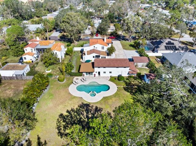 Perched high above sea level in a non-flood zone, (approximately 15’), this exceptional 1923 Spanish Mediterranean Revival Estate sits on nearly one Acre in the heart of Gulfport. The property features two structures with a combined 4 bedrooms and 5.5 bathrooms, including a beautifully preserved 3BR/3.5BA main residence, a versatile two-story carriage house, and a detached 2-car carport showing preserved wood rarely seen in the area. The main home showcases original hardwood floors, exposed wood-beam ceilings, graceful arches, two gas fireplaces, and hurricane-impact windows throughout. First floor layout includes formal living room with gas fireplace, formal dining room with large windows, a sunlit family room, a quaint powder bath and an en-suite guest bedroom or first floor primary with a fireplace! In the well appointed gourmet kitchen you will find heart-of-pine floors, gas range with 6-burner gas range with griddle, stainless steel appliances, a step-down walk-in pantry and more arches! Upstairs, a spacious primary en-suite features a walk-in dressing room, and access to the quintessential Spanish-style balcony. The guest bathroom comes with separate shower & claw foot tub, while the third bedroom enjoys the possibility of having its own future south-facing private balcony. The detached carriage house includes a guest en-suite, laundry room, two-car garage, one-car carport, and an upstairs flex room equipped with a full bath ideal as a home office, a studio, a gym, or a play room, you decide! Outdoor living is exceptional with a magnificent Resort-Style heated saltwater pool and spa with built-in self cleaning system, and lush fully fenced grounds. Encompassing an entire block from north to south, the extensive south-facing rear backyard with gate access, provides additional parking for large vessels - RV or boat, as well endless possibilities for a tennis, pickleball or basketball court for memorable outdoor entertaining. Conveniently located just minutes from Gulfport's vibrant waterfront district, award-winning beaches, downtown St. Petersburg, Tampa, and Sarasota, this remarkable Estate presents a rare opportunity to own a 1920’s classic that perfectly balances timeless charm, and modern comfort.