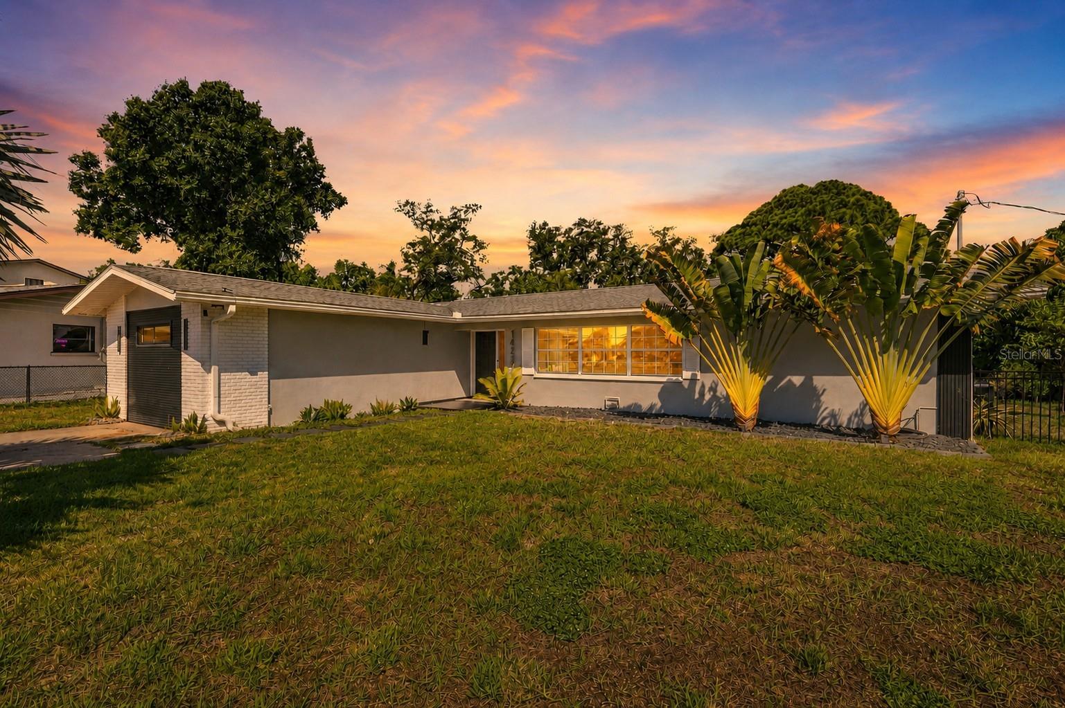 Located on an oversized quarter-acre lot tucked away on a quiet cul-de-sac, this beautifully updated 3-bedroom, 2-bath home offers a bright, open feel with clean lines and high-end, stylish finishes throughout. The home has a thoughtful layout, with the primary suite overlooking the lush backyard, while the other bedrooms sit on the opposite side with separate access to the guest rooms. The true centerpiece is the incredible backyard, masterfully designed for high-end entertaining, relaxing, and enjoying Florida living year-round. Framed by a striking center palm tree, the sparkling pool overlooks an expansive tropical setting filled with mature fruit trees—including coconut, tangerine, passion fruit, mango and guava—creating your own private retreat. Stretching across the entire rear of the home is an impressive, custom 60-foot pergola x 13 ft.  This massive architectural feature is smartly divided into four balanced sections: two expansive 24-foot spans boasting a premium, flexible retractable roof system, flanked by two perfectly proportioned open-air sections. Completing this luxury outdoor living space is a full outdoor kitchen, fridge and grill with storage, a thoughtfully designed area suitable for a future accessory dwelling unit (ADU), providing endless possibilities for guests, extended family, or additional income potential. Enhancing the courtyard space, the accent walls are finished in a premium Romabio Classico Limewash. This high-end finish provides an authentic, Mediterranean style with incredible durability; it acts as a breathable coating that repels heat transfer and is formulated to never chip or peel under the Florida sun. The oversized lot offers ample parking and gated access on both sides of the property, making it easy to accommodate boats, trailers or RVs. With plenty of open yard remaining, there is still room to customize the outdoor space to fit your lifestyle. The home is set back from the street, windows and doors face the lush yard with plenty of distance to create ultimate sense of privacy.  The interior space is perfectly finished. The kitchen features granite counters, stainless appliances, an abundance of counter space, and a newly installed range hood. The area overlooks the pool, giving you easy access to the patio for flawless indoor/outdoor entertaining. Indoor comfort is fully secured by a premium Trane A/C unit, celebrated for its legendary reliability and perfect, uninterrupted climate control. The floors are a wood-look LVP that is anything but ordinary, flowing throughout the home to deliver a highly elevated feel. Both bathrooms are updated and stylish, and there’s a large indoor laundry area with large-capacity washer/dryers that will convey. Located in a peaceful, residential neighborhood with no HOA restrictions and approved for short-term rentals, this property presents an outstanding opportunity as a primary residence, vacation home, or income-producing investment. Its desirable location provides convenient access to Gulf beaches, shopping, dining, parks, and entertainment. Due to the high elevation, no flood insurance is required. Whether you're searching for a move-in-ready home with resort-style outdoor amenities or a property with excellent short-term rental potential, this exceptional home offers a rare combination of style, flexibility, and outdoor living that's difficult to find. See the 2 minute video walk-through for the full experience of this property.