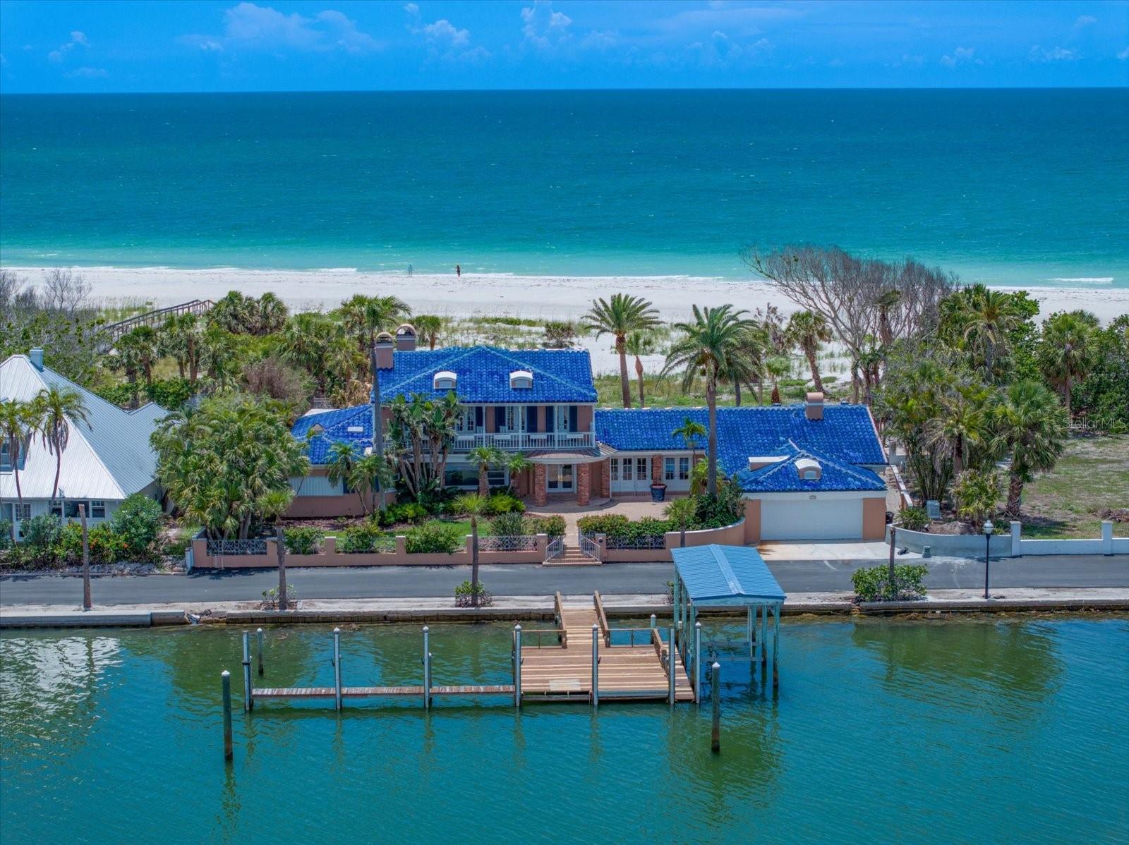 Nestled in the coveted, gated 11-home community at the north end of Clearwater Beach, 1114 Mandalay Point offers a truly rare chance to own one of the most extraordinary waterfront properties on Florida's Gulf Coast. Spanning over an acre, this estate delivers full Gulf-to-Bay frontage - 140 feet on the beach side and 137 feet on the bay side - providing unmatched panoramic views of both sunrise and sunset. Stroll down the private road for dinner at the Carlouel Beach & Yacht Club - or go by boat. This property is a boater's dream, offering protected deep-water dockage and a covered boat slip with quick access to the Intracoastal Waterway and Gulf of Mexico.
The existing 5-bedroom, 4.5 bath home features vaulted ceilings, two fireplaces, separate master suite with sitting room and balconies overlooking the gulf and bay, dining room with a wall of French doors overlooking the bayside courtyard - all ideal for reimagining to reach its full potential. Whether you envision restoring the current structure or building a custom Gulf-to-Bay masterpiece, 1114 Mandalay Point presents an unrivaled setting for luxury waterfront living.