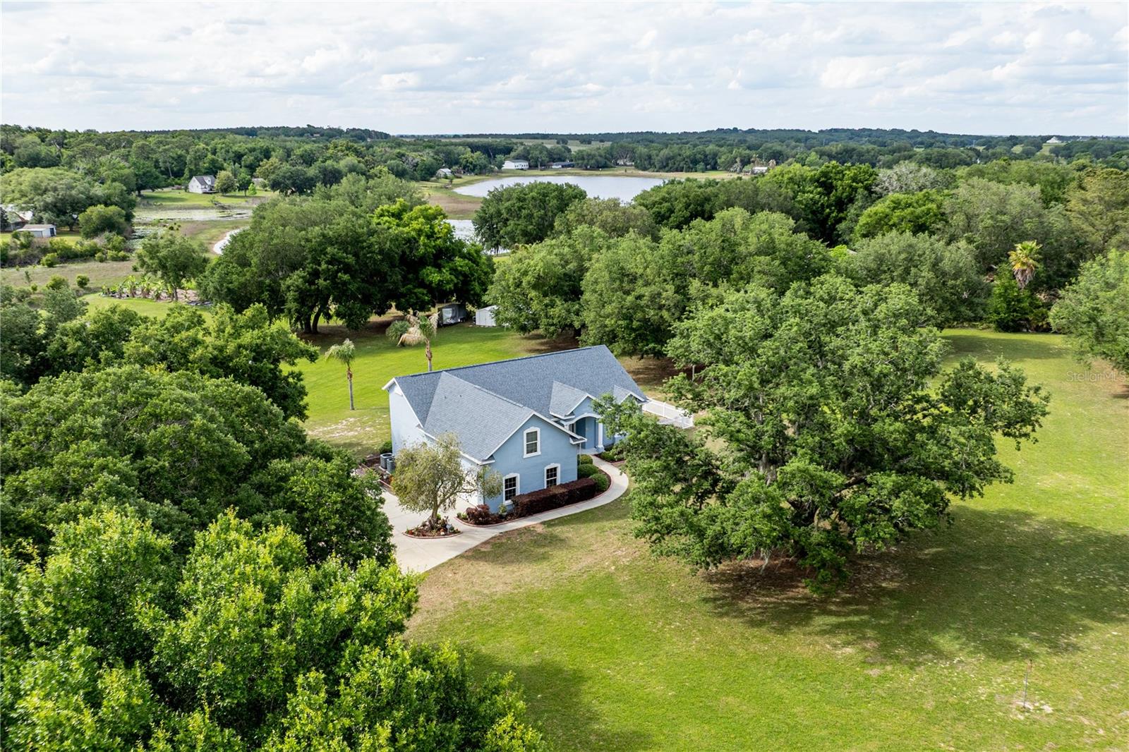 Welcome to your private slice of country living at 25101 Turkey Lake Rd ~ where space, comfort, and scenic beauty come together on nearly 8.5 acres, including approximately 3.5 acres of high-and-dry usable land. Nestled in the rolling hills of Howey-in-the-Hills, this impeccably maintained estate offers a rare blend of privacy, elevation, and convenience and just minutes from shopping, dining, major roadways, and only about 10 minutes from the renowned Mission Inn Golf Resort. 

Set at the end of a long winding driveway, the home features 4 bedrooms, 3 bathrooms, and an oversized 2-car garage (over 500 sq ft). Surrounded by mature oak trees and natural landscape, the property extends into a peaceful, protected conservation-style buffer creating your own private nature preserve that enhances both privacy and tranquility. Bring your RV, build a workshop, or design your dream additions without limitations!

Inside, the home showcases timeless craftsmanship with real wood trim, crown molding, and wood-trimmed windows; offering a level of quality that stands apart from typical new construction. The open concept floorplan is filled with natural light, with large windows framing stunning views and unforgettable sunsets. The spacious living room features high ceilings and direct access to the screened lanai, creating seamless indoor-outdoor living.

The kitchen and dinette combination is both functional and inviting, featuring granite countertops, ample cabinetry, and all appliances included. The dining nook overlooks the property, making every meal feel like a retreat.

The main primary suite offers tall ceilings, private lanai access, and serene views, along with an en suite bathroom featuring a garden tub, separate walk-in shower, updated quartz countertops, a large walk-in closet, and private water closet. A second primary suite with its own en suite bath provides flexibility for guests or multi-generational living. The third bedroom and guest bath are conveniently located off the kitchen, while the fourth bedroom upstairs offers ideal space for a home office, guest suite, or bonus room.

Step outside and take in the beauty of the mostly cleared land yet balanced with mature trees for shade and character without sacrificing usability.

Notable updates and features include a 2018 roof, dual HVAC systems (main system replaced in 2018 and an additional split system replaced in 2023), a whole-house EC4 OxyTech filtration system, and included storage sheds. The property also benefits from a 2019 survey with wetland delineation already completed, and its location in Flood Zone X means no flood insurance is required.

Enjoy the benefits of a “country club lifestyle without the dues” ~ located close enough to experience championship golf at El Campeón, spa amenities, and dining at La Hacienda and Nicker’s, yet free from HOA restrictions. 

This property offers a level of peace, privacy, and quality that is increasingly rare in Central Florida. If you’re searching for room to breathe without giving up modern comforts and convenience ~ 25101 Turkey Lake Rd is a must see. Call for your Private Tour Today! All information recorded in the MLS is intended to be accurate however, it should be independently verified by buyer and their agent.