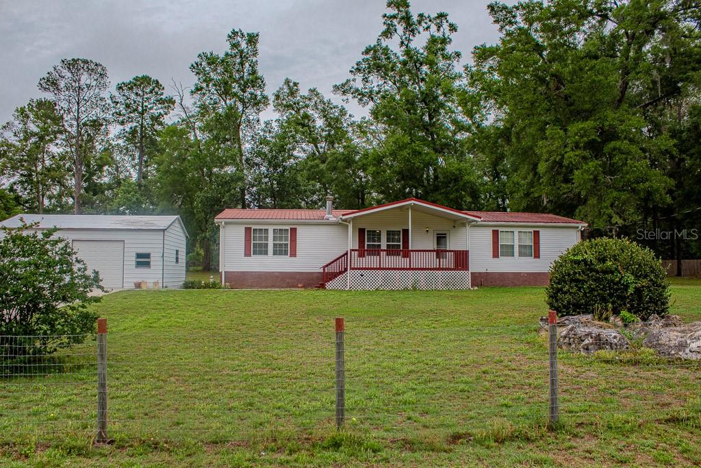 Peaceful Country Living Near High Springs! Nestled on just over an acre in the quiet community of Sherwood Forest, this well-maintained 3-bedroom, 2-bath double wide mobile home offers the perfect blend of comfort, privacy, and functionality. Fully fenced and equipped with well and septic, this property is ideal for those seeking space and freedom without HOA restrictions.
The home showcases true pride of ownership with a spacious layout, a large covered front porch perfect for relaxing, and a covered, enclosed rear porch that adds extra living or entertaining space. A handicap-accessible ramp at the rear of the home provides added convenience and accessibility.
Outside, you’ll find a detached block 2-car garage/workshop with one electric door—perfect for storage, hobbies, or projects. Located just outside of High Springs in Columbia County, this property offers a peaceful setting while remaining close to outdoor recreation, including O'Leno State Park. Enjoy small subdivision living with a quiet, tucked-away feel while still being convenient to town amenities.