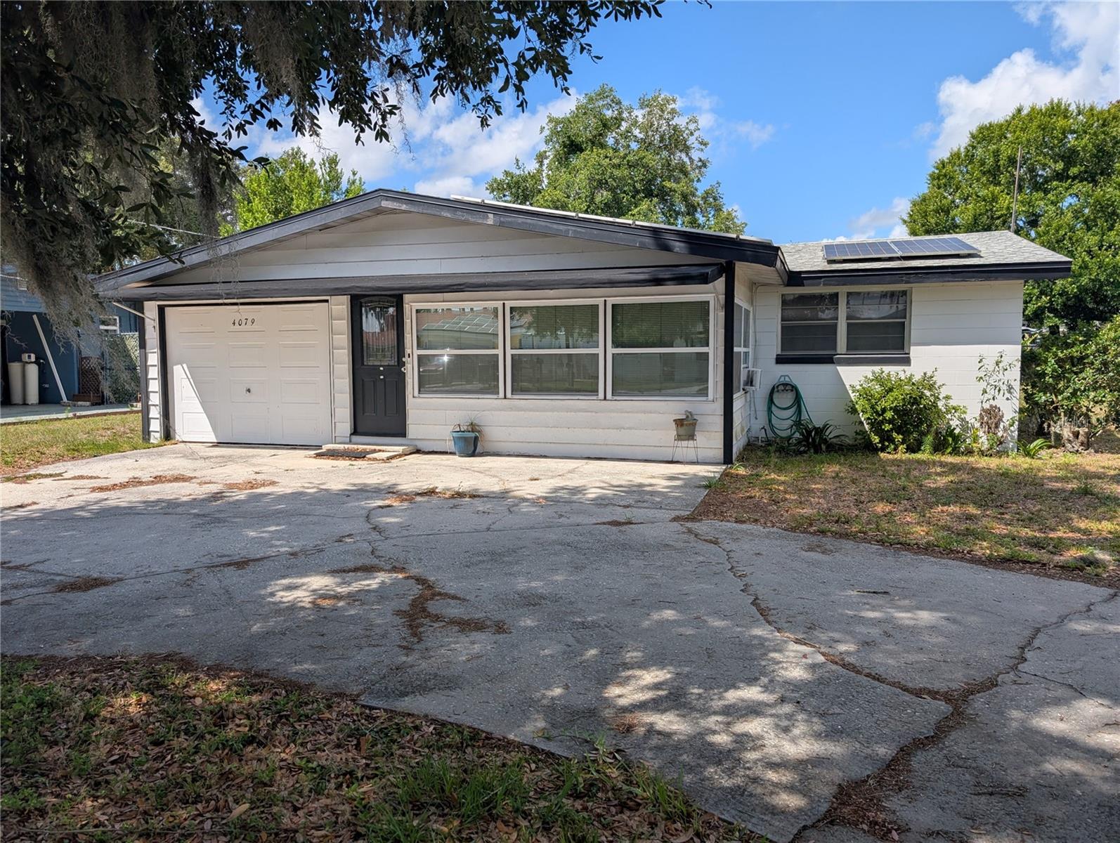 Renovation opportunity at 4079 Lake Marianna Drive. NO HOA, this 3-bedroom, 2-bath home features a circular drive, single car garage, front family room with views of Lake Marianna, newer solar panels, and a new roof installed at the same time as the solar system. The large, fenced backyard includes two extra-wide gates for boat or RV access, plus a shed, workshop, and air-conditioned outbuilding. The home needs repairs and updating and is currently cooled by window units rather than central air.  Central Air was removed, but ducts remain. Bring your vision and make it your own. Close to Winter Haven Regional Airport!