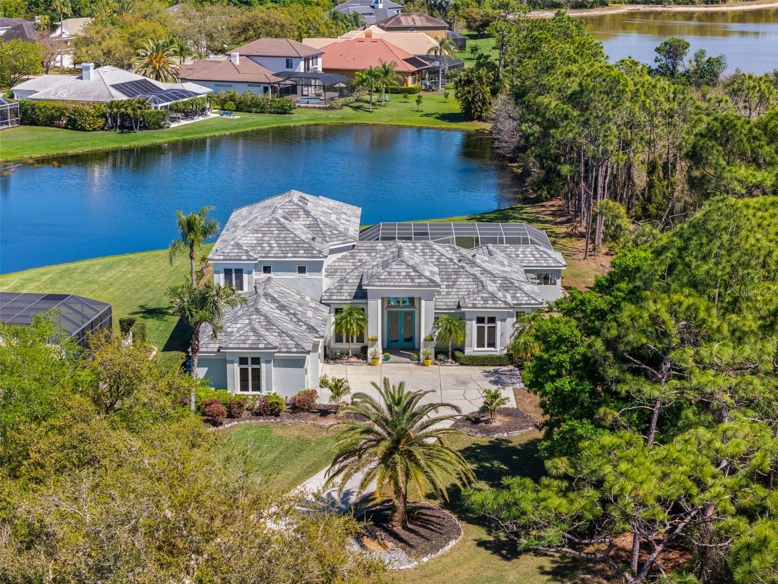 Welcome to an extraordinary offering in the highly sought-after River Club community, where timeless elegance meets luxury on an expansive, private homesite. Tucked away on a quiet cul-de-sac, 7517 Coventry Court commands attention with its oversized three-quarter acre lot, perfectly positioned with a serene county preserve on one side and tranquil water views stretching across the rear. This rare setting offers both privacy and picturesque beauty, creating a true sanctuary in the heart of Lakewood Ranch. Designed for both refined living and effortless entertaining, the home showcases an expansive outdoor oasis. The oversized lanai features a 16’ x 30’ resort-style pool, separate spa, fully equipped outdoor kitchen, and dedicated pool bath, all enhanced by integrated audio for the ultimate indoor-outdoor lifestyle. Multiple oversized siding glass doors seamlessly blend interior and exterior spaces, inviting in natural light and stunning views.
Inside, the thoughtfully designed floor plan balances comfort and sophistication. The primary suite is a private retreat, complete with a spa-inspired shower and elegant finishes. Entertain in style with a dedicated cinema room upstairs featuring an overhead projector and 100-inch screen, as well as a separate billiards room for gatherings. A second-floor balcony provides an additional vantage point to enjoy the peaceful surroundings. High-end features abound, including tray ceilings, crown molding, built-in shelving in both the dining room and office, whole-home audio (extending to the lanai and outdoor kitchen), and designer lighting with under- and over-cabinet illumination in the kitchen. Ceiling fans are thoughtfully placed throughout for year-round comfort. Practical upgrades add peace of mind, including a new roof (2025), new hot water heater (2023), and a full exterior repaint and waterproofing completed in 2022. The spacious three-car garage offers ample storage, while a private mailbox adds a touch of distinction. Located within a golf cart-friendly community with low HOA fees of just $990 annually, River Club offers the perfect blend of luxury and lifestyle. Enjoy close proximity to the world-class shopping, dining, and entertainment of UTC, along with access to top-rated schools. This is more than a home, it’s a statement of elevated living in one of Lakewood Ranch’s most desirable enclaves.