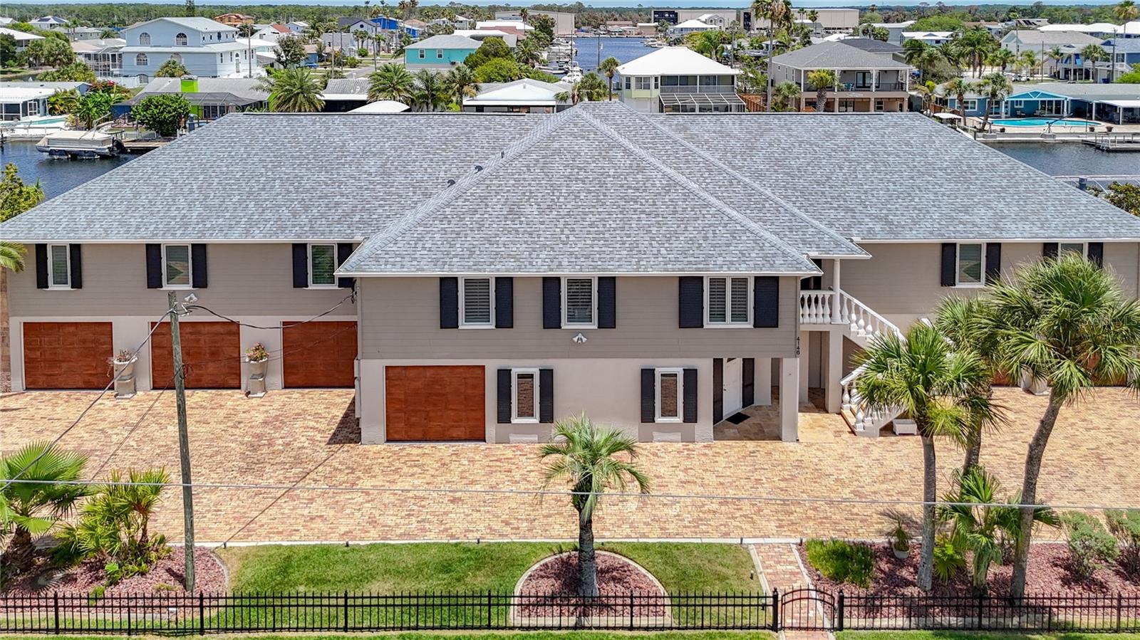 ONE OF A KIND 5 bedroom + 4.5 baths + massive 6 car gar with this luxury waterfront custom built home in Hernando Beach. Discover this extraordinary move-in ready luxury custom home, meticulously maintained to the highest standards. This expansive layout with wood plantation shutters throughout, a 6-car garage with circular paver extended driveway is situated on three spacious lots with an impressive 180 feet of deep canal waterfrontage and no locks. There is a private boat launch, floating dock, fixed dock with gazebo, and a 10k lb boat lift. This sprawling estate offers 3,756 sq ft of elegant living space. Designed for durability and style, the home boasts a new roof and gutters in 2/2026, a reinforced seawall, column and lintel tie-beams, Hardi-Plank cementitious siding, Pella windows, alarm system, and both electronic and manual storm shutters,  while a whole-house filtration system and 2 of the 3 AC systems are new to provide reliability and comfort. The concrete driveway is accented with reclaimed Chicago bricks and illuminated stone columns. Outdoor living is elevated by a spectacular 126-foot covered waterfront porch featuring cypress wood ceilings and an outdoor kitchen with 2 Big Green Egg grills, and a Viking grill—ideal for enjoying picturesque waterfront views, host family gatherings, or entertaining guests. You’ll be greeted with marble steps with grand balustrades that lead to a stately foyer and an open-concept great room with soaring ceilings, a grand fireplace, Tigerwood floors, and a classic cherry wood wet bar with Sub Zero appliances, double layered Bahia blue granite, stained glass, and a marble powder bath. The remodeled chef’s kitchen is a dream come true, complete with soft-touch wood cabinetry, a spacious pantry, premium granite countertops, a gas cooktop and oven, commercial grade warming drawers, Sub Zero refrigerator that sits inside custom cabinetry with built-in spice racks, 2 Miele dishwashers, a copper sink, and marble floors, all overlooking the family room and reading loft. The master bedroom suite is a luxurious retreat with vaulted ceilings, a sitting area, wet bar, double faced fireplace, jetted tub, a walk-in wardrobe room with custom-built cabinets, Tigerwood floors with double French doors leading to the expansive balcony. On the ground floor, over 3,700 sq ft is devoted to a massive 6-car garage, workshop, 1,000 bottle wine cellar with concrete walls and ceiling, a solid custom door, brick floors, and custom venetian-styled painting, and additional flex spaces. The ground floor has been thoughtfully created to be an easy in-law/apartment with a living room/dining room, bedroom, bathroom and plumbed for kitchen.  The main living quarters are thoughtfully positioned above the flood plain for added peace of mind. This one-of-a-kind Hernando Beach waterfront estate blends luxury, function, and lasting quality for discerning buyers seeking the best in coastal living. Fish for sheepshead, redfish, blue crab and many others right from your dock. The community is golf cart friendly and allows short-term rentals with no HOA, no deed restrictions, making it perfect for full-time residents, or potential AIRBNB income. Minutes to US 19, walking distance to several amazing local restaurants and close to the Suncoast parkway for quick access to the airport, Tampa, Clearwater and St. Pete Beaches. Also close to Pine Island, Homosassa Springs, the famous Weeki Wachee live mermaids & Tarpon Springs Sponge Docks.