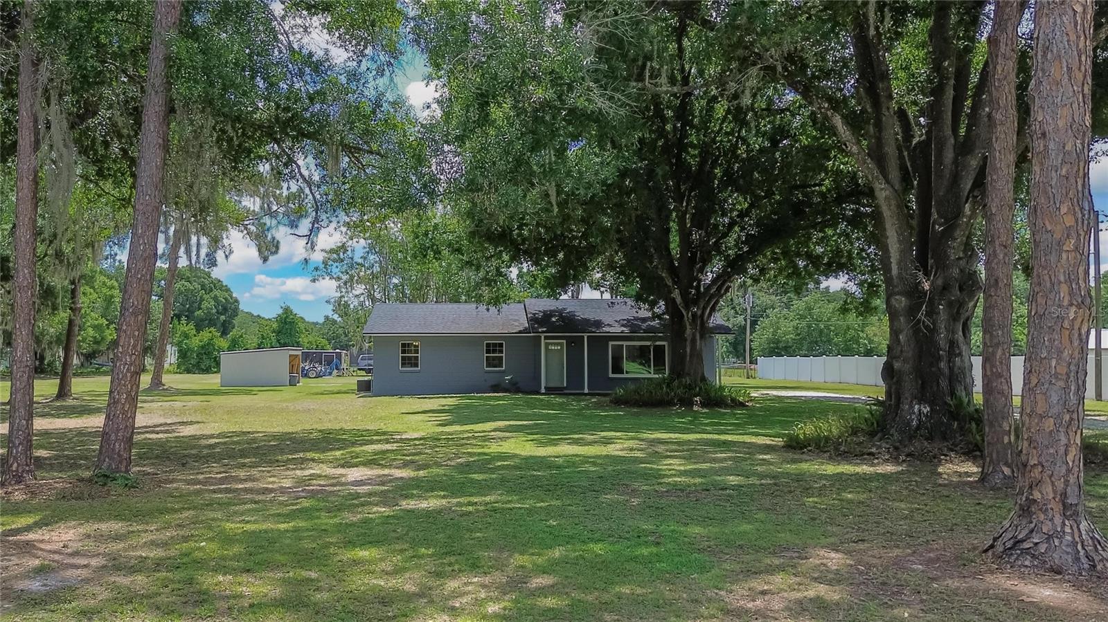 Welcome to this Adorable 3-bedroom, 2-bath Block Home, Nestled on 5 Beautifully landscaped Acres at the end of a peaceful cul-de-sac. This Private Oasis is like a Playground for All Ages—imagine fishing off your own Wooden Dock in the Private Pond, watching your family play freely in the expansive yard, sipping your coffee admiring the Wildlife and spending evenings around the Fire Pit. The property includes a large 20 by 22 workshop/office with AC( Nice deck outside), and the Home is Filled with Bright, Open-Concept Living—featuring an Beautifully updated  Kitchen with Stainless Steel Appliances, a large Breakfast Bar, and a Wood-Burning Fireplace. Both Bathrooms are tastefully updated and all Bedrooms are spacious, with an inside laundry room with shelving. Outside, the deck offers both open space and a Screened Enclosure, perfect for relaxing. The land is mostly cleared with some shaded areas and the house sits on high and dry land out of a flood zone —though the pond and some surrounding area in an A flood zone.With a 2020 Roof and 2024 AC ths home offers Modern Comforts and Peace of Mind. You’ll also enjoy being close to everyday conveniences—just over a mile from a Publix and with quick access to a nearby highway. This home offers both seclusion and convenience—truly a rare find!