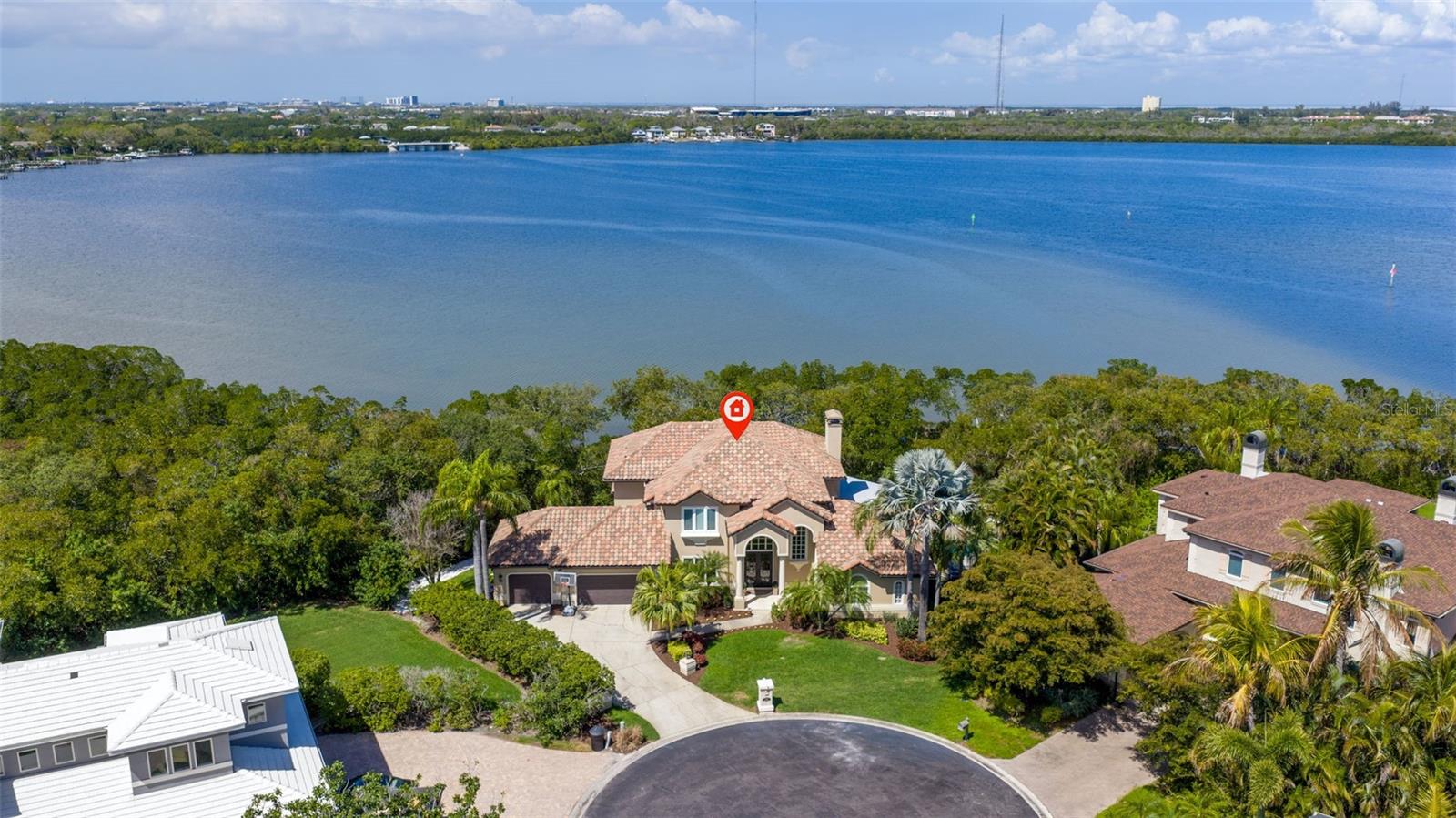 EXPANSIVE WATERFRONT HOME IN GUARD-GATED CAYA COSTA WITH 199 FT OF WATERFRONTAGE, 4 BEDROOMS + OFFICE + MEDIA ROOM + GYM, SALTWATER POOL, BOAT SLIP WITH 16,000 LB LIFT, AND 3-CAR GARAGE. Located in the guard-gated waterfront community of Caya Costa in Northeast St. Petersburg, this executive residence offers 4,384 sq ft of living space on a .34-acre lot with 199 ft of protected waterfront and wide open-water views along Weedon Island Preserve. Designed for both everyday living and entertaining, the home combines boating access, privacy, and a flexible floor plan rarely found in this location. The home includes 4 bedrooms, 3.5 bathrooms, private office, media room, gym, butler’s pantry, 3-car garage, and an extra-wide driveway for additional parking. Interior features include 10-ft ceilings, 8-ft doors, a dramatic two-story foyer, wood-burning fireplace, engineered wood flooring throughout (2024), and a wet bar with wine refrigerator for entertaining. The chef’s kitchen features Wolf, Sub-Zero, and Miele appliances, dual islands for gathering and meal preparation, abundant storage, and a butler’s pantry with prep kitchen. The private office includes custom built-in cabinetry and large windows providing natural light and a quiet workspace. The waterfront primary suite includes a sitting area overlooking the bay and direct access to the balcony. The ensuite bath features dual vanities, dual walk-in closets, soaking tub, walk-in shower, and separate water closet. Outdoor living is centered around the waterfront setting. A large open balcony accessed from the primary suite and media room overlooks the pool and backyard, providing a private vantage point for sunrise and sunset views. The covered lanai includes an outdoor kitchen with bar, dining area, TV, and lounge space overlooking the pool & water. The PebbleTec saltwater pool and spa (2021) overlooks the waterfront with updated pavers, pool equipment, and propane heater (2021). Mature tropical landscaping surrounds the backyard, creating a private outdoor setting with wide open-water views and no rear neighbors looking into the property. Gasparilla Drive NE is a quiet cul-de-sac with only 5 homes sharing a deep-water dock with 6 slips. The assigned slip includes a 16k lb boat lift (2018), water, and 30-amp shore power. Boaters enjoy calm protected water with direct access to Tampa Bay in under 10 minutes (no fixed bridges). Additional outdoor features include a kayak/paddleboard launch with storage, spray mosquito system, side yard turf (2026), and open water views with no neighbors. The home sits at 10.55 ft elevation and was not affected by the storms of 2024. Flood insurance is only $1,143/year. Recent improvements include three AC units replaced (2024-2025), tile roof (2017), flat roof under the upstairs balcony replaced (2026), and balcony decking replaced (2026). Additional features include an elevator and attic storage. Caya Costa offers a secure guard-gated entrance with a monthly HOA of $400. Conveniently located near Publix, Whole Foods, Target, Starbucks, dining, and everyday conveniences. Shorecrest Preparatory School and Canterbury School are approximately five minutes away. Downtown St. Petersburg is a 15-minute drive, and Tampa International Airport is approximately 20 minutes away. This property offers a rare combination of protected boating water, expansive waterfront views, gated privacy, and a secluded backyard setting rarely found in Tampa Bay waterfront homes.