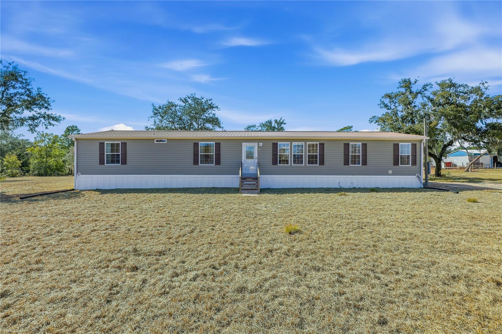 BRONSON 5 ACRES WITH A 4 BEDROOM/3 BATH HOME ON A PAVED ROAD! Beautiful, well maintained 2021 manufactured home on 5 acres. Located on a paved road. This custom ordered home is loaded with upgrades, including tray ceilings, tape-and-textured walls, crown molding, upgraded baseboards, and an open floor plan.
The spacious layout offers 4 bedrooms and 3 bathrooms with luxury vinyl plank flooring throughout. The home comes fully furnished—just bring your personal belongings and move right in.
Kitchen features include a large island with stools, farmhouse style sink, hidden pantry, and an oversized window with an awesome view of the backyard that fills the space with natural light.
The primary bedroom is light, bright, and spacious with a generous walk-in closet. The primary bathroom includes a custom built shower and beautifully designed layout.
Outdoor amenities include a 24'× 20' metal garage with concrete floor, electricity, and water, plus two 12'× 20' storage buildings, both with electricity and water—one currently used as a greenhouse. Enclosed pump house. Perimeter fenced. This is a winter home so it's like new!
Perfect opportunity for peaceful country living with modern upgrades already in place. Come see what Levy County has to offer! Book your appointment today!