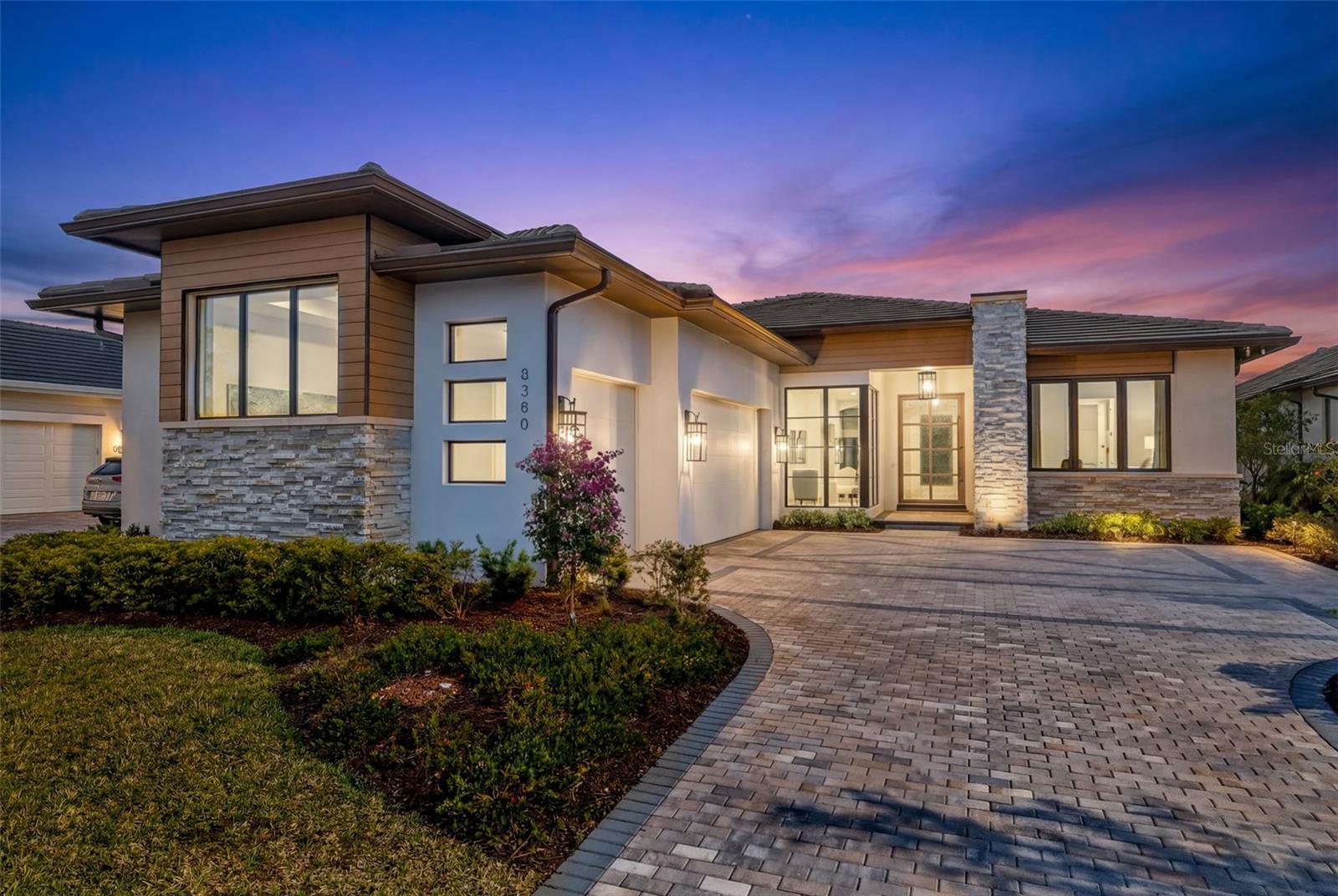 Stunning Award-Winning Former Model Home – Better than new, turnkey furnished, and no waiting.
This exceptional residence is a must-see for those seeking elevated luxury and thoughtful design. As a former model home (with over $150K in additional after closing improvements), this property showcases premium upgrades and architectural details throughout, blending modern transitional style with warm wood tones, custom tile work, and designer finishes. Step through the striking crackled glass & iron pivot front door into a grand marble foyer featuring custom moldings, exquisite ceiling details, and elegant lighting that sets the tone for the impeccable craftsmanship found everywhere. Highlights include a dramatic fluted wood feature wall with a linear fireplace, custom ceiling treatments with cove lighting, a hidden walk-in pantry with custom built-ins, and a boutique-style owner’s closet that feels like a dream. The gourmet kitchen is a chef’s paradise, complete with upgraded professional appliances, a stunning waterfall island, and an expansive walk-in pantry designed for both beauty and ultimate organization. Sun-drenched and serene, the outdoor living space is truly breathtaking. Enjoy unobstructed, sweeping views of nature from an inviting lap pool, custom pool deck, and fully equipped outdoor kitchen — all protected by StormSmart storm screens. The pool bath features floor-to-ceiling decorative tilework for a spa-like touch. A show-stopping wrap-around glass wall with sun shades floods the home with natural light while framing the peaceful surroundings. Additional luxury features include: Stunning window treatments throughout, with room-darkening draperies and shades. Versatile bonus room with pull-out sofa bed and built-in cabinetry. Dedicated office with custom moldings and thoughtful built-ins. Control-4 home automation and whole-home sound system. Landscape lighting, newer epoxy garage floor, and freshly painted interior (including the garage) Better than new and fully furnished, this lock-and-leave home exudes sophistication and tranquility in every detail. Located in Wild Blue, one of Lakewood Ranch’s most desirable new luxury enclaves, residents enjoy resort-style amenities including tennis and pickleball courts, a restaurant and bar, state-of-the-art fitness center, golf simulator, and more. The location is incredibly convenient — just minutes from shopping and dining at Waterside Place and University Town Center. This is truly a rare opportunity to own a turnkey, move-in-ready luxury home in a premier community. Your dream lifestyle awaits!