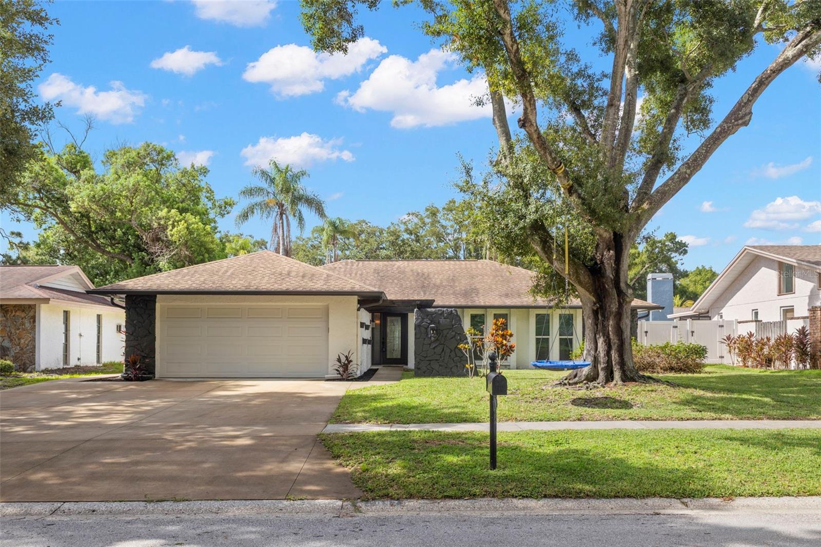 Virtually Staged. Welcome to this beautifully updated home in Northwoods Estates, located in northern Clearwater near shopping & major thoroughfares.  Thoughtfully designed with an open, easy-flowing floor plan, the home features wood-look luxury vinyl plank flooring throughout, six-panel doors, & impact windows in most areas but not any of the sliding doors.  The garage door is also hurricane rated.  From the moment you arrive, the expanded three-car driveway, pergola-covered entry, raised planter box & hanging wall planters create inviting curb appeal.  Inside, a spacious foyer opens to a den or media room with French doors, while the hallway leads to a fully updated guest bath  & generously sized bedrooms.  Each bedroom includes double closets, & the primary suite adds a walk-in closet for exceptional storage.  The primary bathroom has also been updated & includes a sunken shower area, modern vanity, & refreshed fixtures. The kitchen, dining room, breakfast area & family room connect seamlessly, creating comfortable spaces for everyday living & entertaining.  The kitchen offers granite countertops, a closet pantry, recessed lighting, an updated sink with pull out faucet, & stainless steel appliances.  The adjoining family room features a vaulted ceiling & a wood-burning fireplace as its centerpiece.  Outdoors, enjoy Florida winters from the covered patio, which extends to a welcoming corner seating area just across the open patio area. Your yard has vinyl fencing for privacy & a grassy area for your pets or guests. A large interior laundry room provides added convenience with a front load washer & dryer, sink, closet, accent wall with hooks & storage cabinets.  With its updates, storage, outdoor living areas, &  impact windows throughout most of the home, this property offers comfort, style, & peace of mind.   HVAC 2022,  Square D electrical panel, water heater 2016, roof 2010
