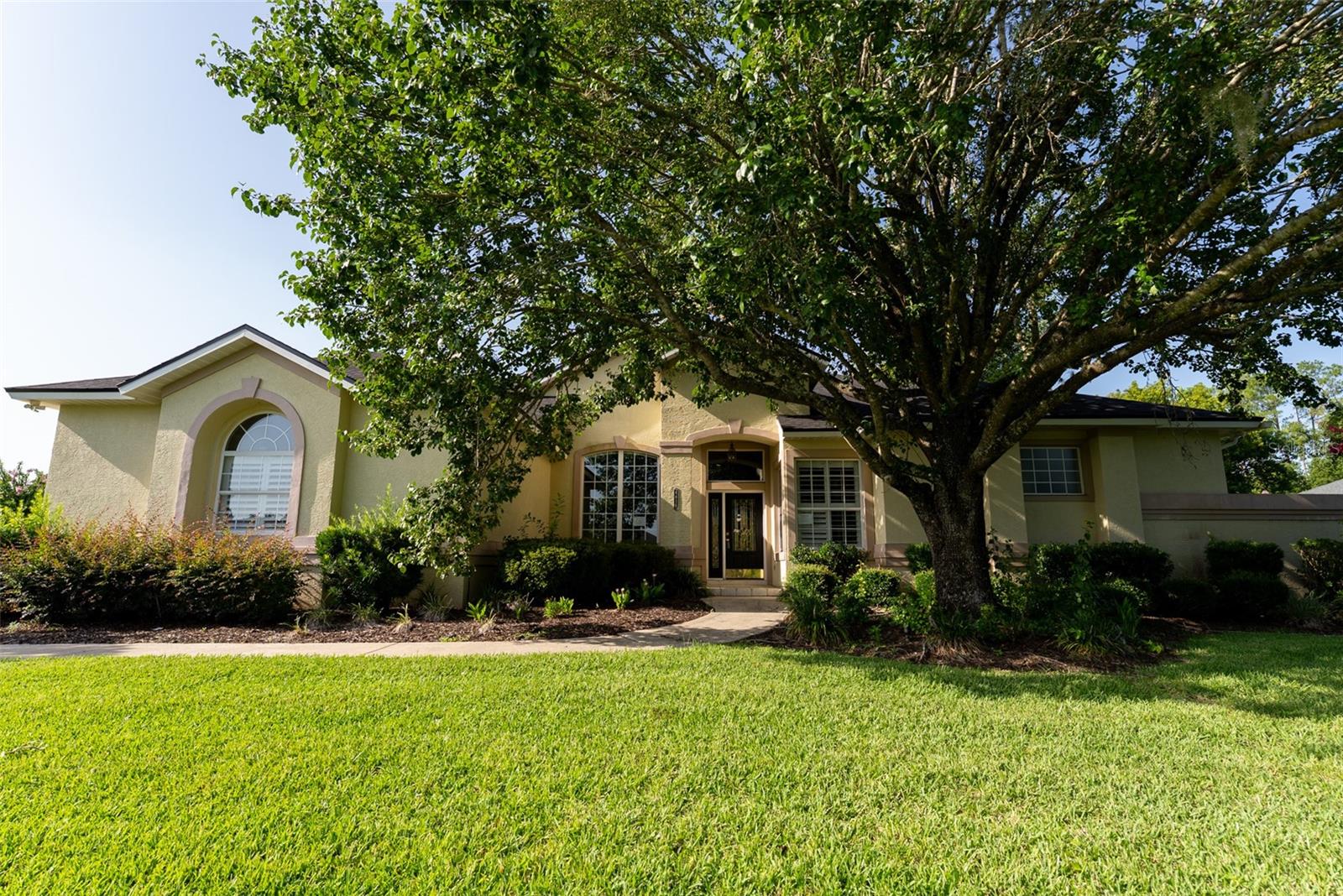 This 4-bedroom, 2.5-bath home is situated on just over one-half acre within the city limits and features an in-ground pool, multiple living areas, and a split-bedroom floor plan. The entryway includes approximately 12-foot ceilings, and crown molding is found throughout much of the home.  The kitchen is equipped with solid wood cabinetry, granite countertops, a tile backsplash, stainless steel appliances, a breakfast bar, and a breakfast nook. Additional interior spaces include a formal dining room with a tray ceiling, formal living room, family room, flex room, and a powder room.  The primary suite includes a tray ceiling, en-suite bathroom with a garden tub, walk-in shower, double vanity, private water closet, and two walk-in closets. The home also includes three additional bedrooms, a full guest bathroom, and a powder room.  French doors lead to a covered rear porch with a wood ceiling and ceiling fans. The outdoor kitchen includes built-in amenities, including a gas hibachi-style grill. The backyard features mature landscaping, a built-in fire pit, an in-ground pool with a waterfall feature and sun shelf, and a paver pool deck. Home features a 2-car garage with built-in storage cabinets. Roof was replaced in 2022.