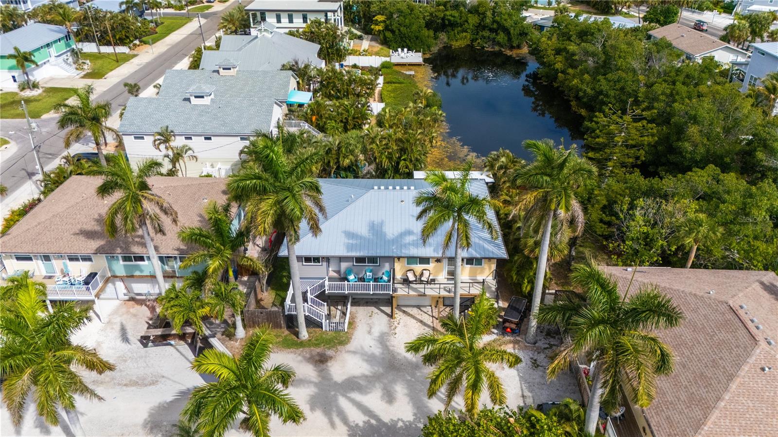 JUST REDUCED! This elevated two-bedroom, two-bath half-duplex home in Holmes Beach offers an ideal beach getaway with the added benefit of allowing weekly rentals and no HOA. Situated on a quiet cul-de-sac, it's just a block away from Beach Access #69. The home features a front deck, perfect for morning coffee, and a back deck for evening cocktails, complete with a stairway leading to a private backyard. Enjoy peaceful lagoon views from your backyard, creating a serene and relaxing setting. Both decks have been updated with Trex decking, known for its durability and longevity, often lasting many years. The backyard also provides ample space for a future pool. Inside, the home boasts a combined living and dining room and a pass-through kitchen. The primary bedroom includes a walk-in closet with a stackable washer/dryer, and the second bedroom and bath are conveniently adjacent to the primary. Recent updates enhance the home's appeal and functionality, including a new AC in 2018, newer kitchen appliances, newer kitchen cabinetry and waterproof vinyl flooring throughout. Significant exterior upgrades were completed in 2021, such as a new metal roof, Hardie board siding, and impact windows and doors. Hardie board siding (fiber cement siding) is recognized for its durability and resistance to weather, pests and fire. Impact windows and doors offer benefits such as enhanced security, noise reduction, increased energy efficiency and protection against extreme weather, potentially increasing property value and lowering insurance costs. A 6-foot privacy fence was also added in 2021. The ground floor features a garage with tandem parking for two cars or space for one car and a golf cart or bikes. Additionally, a non-conforming space offers flexibility for an office, art studio or other uses. This home is centrally located in Holmes Beach, providing easy access to local shops, restaurants, a dog park, a marina and the 63rd Street boat ramp. Holmes Beach, in the middle of Anna Maria Island, is known for its pristine public beaches and offers various activities and attractions.