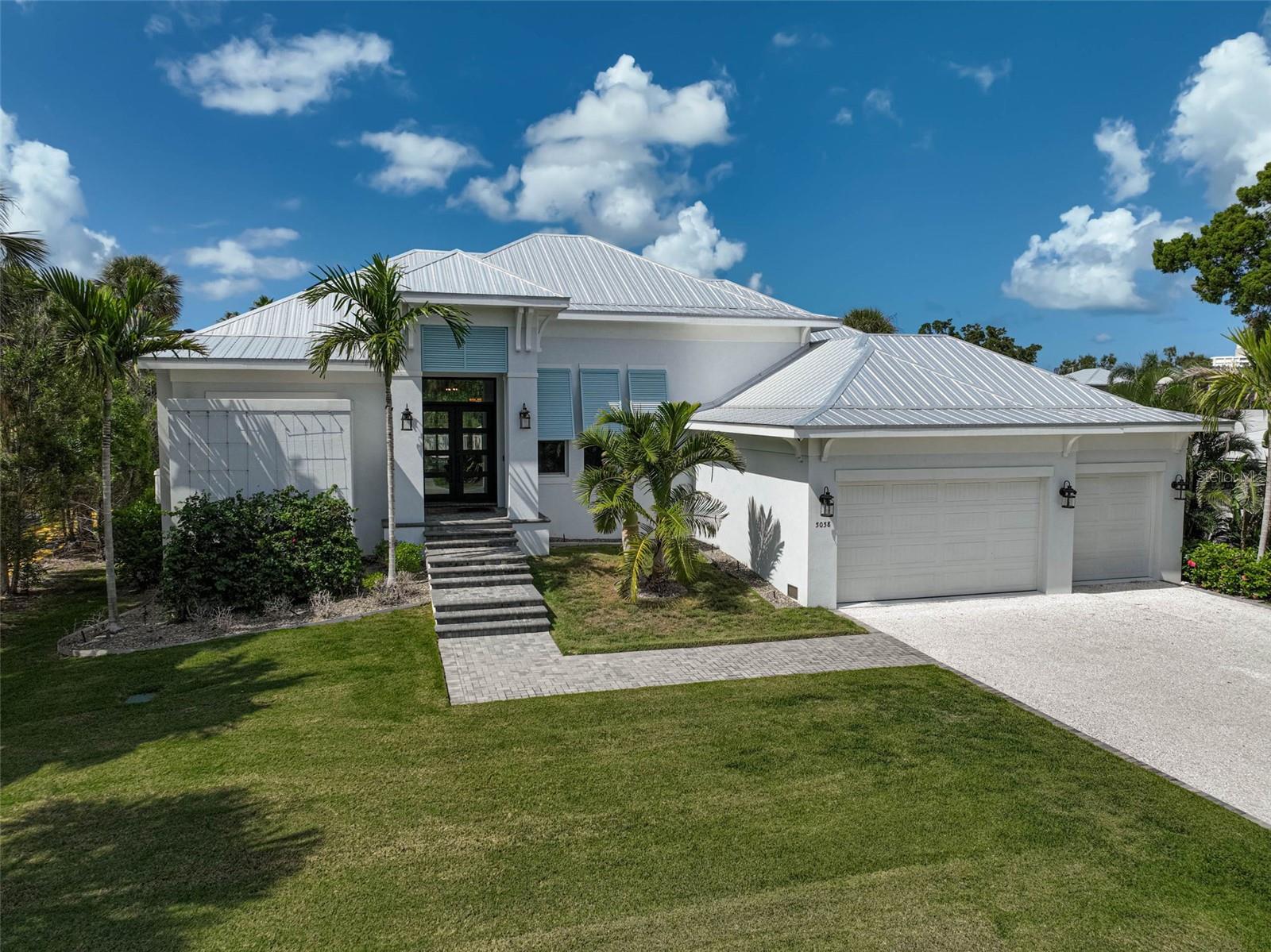 This custom-built home received the “Best Overall” award in the 2021 Manatee and Sarasota County Parade of Homes. Experience the pinnacle of Siesta Key waterfront living in this 2019-built masterpiece by Nutter Custom Construction. Designed with precision and built to last, this solar-powered coastal retreat sits on high elevation and spans over 3,400 living square feet, offering 3 bedrooms, 3 baths, and two versatile flex rooms that redefine modern island living. Every element blends elegance, performance, and peace of mind. You walk into a wide-open floor plan that immediately draws you in. To the left, the primary suite offers total privacy with a spacious bedroom, spa-inspired bathroom featuring double vanities, a soaking tub, glass-enclosed shower with 4 shower heads, and a private outdoor shower with 2 shower heads, connected directly to the master bath a truly open-air sanctuary. To the right, your dedicated office provides focus and functionality and can easily serve as a fourth bedroom, with the flex room ideal for a home office or bonus space. The heart of the home opens to expansive living and dining spaces with a chef’s kitchen showcasing high-end cabinetry, premium flooring, designer lighting, and top-of-the-line Sub-Zero and Wolf appliances. Each guest bedroom includes its own private en-suite bath, offering comfort and privacy for family and visitors alike. A large walk-in pantry and laundry room are conveniently positioned near the kitchen. A whole-home water softening system, an In-wall pest control system with access ports, 2 air conditioning systems to keep the home evenly comfortable during the warmest weather, and 2 tankless water heaters to provide plenty of hot water. An oversized three-car garage for everyday ease. An additional flex room opens to the pool through oversized sliders, perfect for a second office, game room, or guest suite. There are automated window shades in the living room and game room. The home runs entirely on solar power and includes a multi-room sound system that fills the home and outdoor living space with your favorite music. Massive hurricane-rated sliding glass doors wrap the back of the home, creating a seamless flow to your backyard oasis, including landscape lighting and an irrigation system. An Integrated Security System with perimeter cameras provides extra peace of mind. Step out onto the beautiful travertine pool deck, featuring a heated pool and champagne-edged spa, outdoor lounge, and covered dining area with a built-in outdoor chef’s kitchen powered by propane, perfect for entertaining in style, and all with a sunset view. Beyond the pool, enjoy a lush, manicured backyard with direct access to the wide Siesta Key Grand Canal. A dedicated 14,000-pound boat lift allows you to launch your boat with ease, making days on the water effortless. A separate private docking area is available for your friends to arrive by boat or for jet skis. Enjoy kayaking, paddleboarding, and scenic canal rides, or simply relax and take in the sunsets from your extended concrete pad with a built-in concrete firepit, ideal for gatherings by the water. Every detail of this home is custom-crafted, from its hurricane-rated construction and elevated-lot placement to its energy-efficient systems and timeless coastal design. 5058 Windward Ave isn’t just a home, it’s a statement in waterfront living: high elevation, solar-powered, elegant, and built for those who expect the very best on Siesta Key.