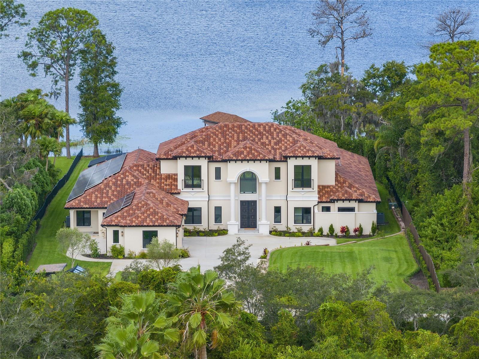 Welcome to 8990 Darlene Drive and embark on a journey of luxury in this 2022-built architectural gem on the prestigious Millionaire's Row in Dr. Phillips, Orlando. Unfettered by HOA, this 3.39-acre lot boasts 120 feet of serene waterfrontage on Pocket Lake. Visualize evenings under the Disney and Epcot fireworks and days of peace on the Butler Chain of Lakes. Step into this 7,776-square-foot luxurious compound, where sophistication meets function and sustainability with many elements of energy efficiency, including fully paid solar panels. Your gourmet kitchen awaits, featuring both induction and gas Wolf ranges, an oversized Sub-Zero fridge, and an air-conditioned wine cellar. Envision entertaining with ease, using your fully equipped outdoor kitchen. This haven offers six elegant bedrooms and eight bathrooms. The primary suite, your personal sanctuary, includes a spa-like bathroom with dual showers, and an outdoor shower. Guests or extended family enjoy privacy in a self-contained one-bedroom apartment with its own fully equipped kitchen and private entrance. Start your days in the home gym, followed by rejuvenation in the dry or wet saunas. Evenings bring joy in the game room. Spanish marble floors throughout the first floor, tall solid wood doors, and a stunning Spanish iron-wrought double front door and staircase enrich every moment. Outside, indulge in your private oasis: a pool and hot tub under Florida's sun or the starry sky. A private dry dock beckons for lake adventures, while a private garden offers moments of serenity and reflection. This isn't just a home; it's a lifestyle of sustainability, sophistication, and exclusivity in one of Orlando's most sought-after locales. Surrounded by world-renowned shopping and in close proximity to Disney, Universal and Sea World parks, it blends privacy, luxury, and unparalleled living.
