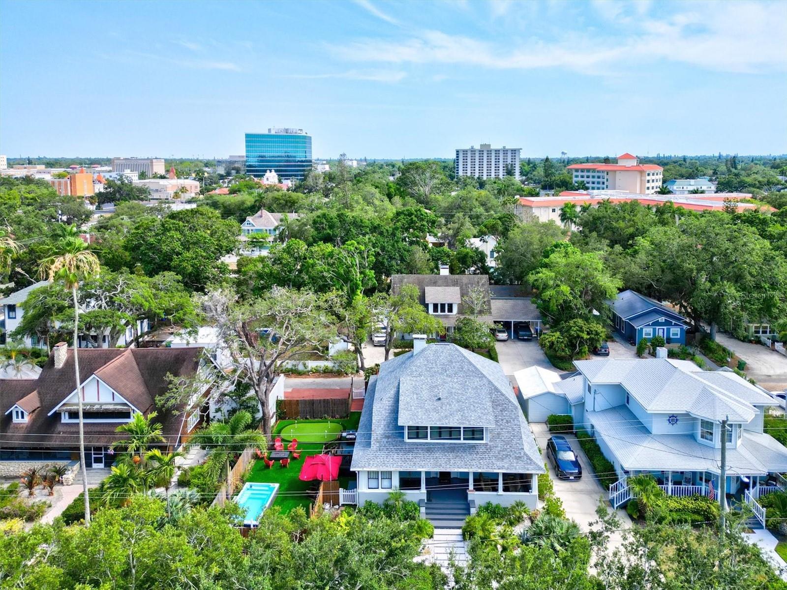Some houses have a story to tell. Others are still writing one. Restored with respect for its past and designed for how we live today, this 1913 home blends preserved architectural detail with thoughtful modern updates. Located in Point Pleasant in downtown Bradenton near Old Main Street, this classic American Four Square offers 4 bedrooms and 5 bathrooms with a layout that feels both traditional and livable. An easy care landscaped front yard leads to the expansive wraparound porch, a natural extension of the home that invites slow mornings and relaxed evenings. Inside, original leaded glass windows and a fireplace anchor the main living space, which flows easily into the family room and kitchen. The family room features impact windows and a full bath, offering flexibility for guests or everyday use. The kitchen and dining area have been thoughtfully opened to create a bright, welcoming space overlooking the side yard. Finished with KraftMaid cabinetry, LG appliances, a Bosch paneled dishwasher, butcher block counters, and a Dekton Entzo-topped island, it balances function and style without losing character. Just beyond, a reimagined butler’s pantry adds a wine refrigerator, dual drink drawers, sink, and additional cabinetry, creating an ideal transition for entertaining. Upstairs, three bedrooms include remodeled ensuite baths, while a fourth bedroom is served by an updated hall bath. The primary bath addition includes a walk-in shower, dual vanities, and a private water closet, designed with comfort and practicality in mind. The outdoor spaces are equally considered. A composite side deck, rebuilt rear porch, and a partially submerged swim spa create a private retreat. A professionally installed putting green, gas fire pit, outdoor shower, and bamboo fencing are complemented by landscape and string lighting that carry the space into the evening. Recent updates include a 2022 roof, HVAC systems (2023 and 2025), 16 impact windows, refinished wood floors, fresh interior paint, updated lighting, and new window treatments throughout. Located just moments from the Manatee River and Riverwalk, this home places you close to dining, boating, and the everyday rhythm of downtown Bradenton while offering a private, character-rich place to come home to. Despite its close proximity to the water, the property is located in Flood Zone X, where flood insurance is typically not required by lenders, offering an added layer of confidence.