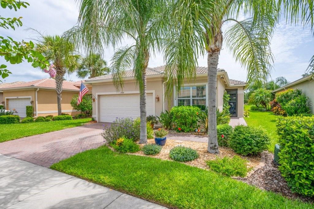 This spectacular move-in-ready Positano model showcases breathtaking water views with no backyard neighbors and is located in Valencia Lakes, Tampa Bay's premier 55+ resort-style community. One of the most desirable floor plans in the Signature Collection, this beautifully maintained home offers 2 bedrooms, a spacious den that can serve as a third bedroom, 2 bathrooms, and a 2-car garage. Exceptional curb appeal welcomes you with a brick paver driveway and walkway, barrel tile roof, and lush tropical landscaping. Inside, the open-concept great room floor plan features large diagonal tile flooring throughout the main living areas and den, complemented by brand-new luxury vinyl plank flooring in both bedrooms for easy maintenance. The impressive foyer boasts an 11-foot coffered ceiling, setting the stage for the home's bright and airy design. The expansive great room is perfect for entertaining, featuring triple 8-foot sliding glass doors that open to the covered screened lanai and capture tranquil long water views. The gourmet eat-in kitchen is a chef's dream with upgraded granite countertops, an undermount stainless-steel sink, an extended 18-inch serving bar, 42-inch soft-close raised-panel pecan maple cabinetry with glass accent doors and lighting, tumble stone marble backsplash, a built-in pantry, under- and over-cabinet lighting, and stainless-steel appliances, including a new dishwasher. The adjoining dining area provides the perfect setting for everyday meals and special gatherings. The spacious primary suite offers peaceful water views, a coffered ceiling, two large walk-in closets, and new luxury vinyl plank flooring. The luxurious en-suite bath features dual vanities with granite countertops, raised-panel maple cabinetry, a walk-in shower with a built-in bench and tile to the ceiling, and a linen closet. The oversized den with double 8-foot doors is ideal for a home office, media room, or guest space. The split-bedroom layout provides privacy for family and guests, while the secondary bath features granite countertops and upgraded cabinetry. Additional upgrades include a new HVAC system, new heat pump water heater, accordion hurricane shutters, screened front entry, designer lighting and ceiling fans, extra recessed lighting, water softener system, gutters, epoxy garage flooring, overhead garage storage, utility sink, custom laundry cabinetry, landscape lighting and a portable solar-powered generator. Valencia Lakes offers an unparalleled resort lifestyle with a 40,000-square-foot clubhouse, fitness center, resort and lap pools, restaurant, tennis and pickleball courts, bocce, walking trails, clubs, entertainment, arts and crafts, and countless social activities. This exceptional home offers the perfect combination of luxury, comfort, and maintenance-free living in one of Tampa Bay's most sought-after active adult communities.