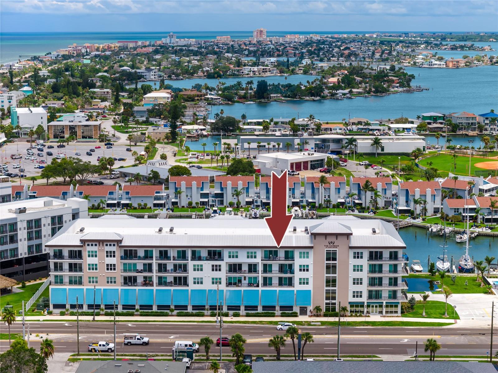 Built in 2022, this impeccably maintained 4-bedroom, 2.5-bath luxury condo offers a rare opportunity to own a modern, low-maintenance waterfront residence in the heart of Madeira Beach Town Center, one of the area’s premier coastal redevelopments. Designed for both upscale personal use and high-performing short-term rentals, this top-floor residence combines contemporary elegance with exceptional income potential, thanks to flexible 2 week minimum rental allowances in one of the few buildings on the Gulf Beaches to permit them. High ceilings, stylish pendant lighting, and neutral wood-grain luxury vinyl flooring create a bright, refined interior, while the open-concept layout flows seamlessly for entertaining and everyday living. The gourmet kitchen is a standout, featuring solid wood 54-inch underlit white cabinetry, a sleek subway tile backsplash, high-end Bosch stainless steel appliances, and a large Cambria quartz island with breakfast bar and built-in wine refrigerator, making it ideal for hosting guests or maximizing rental appeal.

Oversized hurricane-impact sliding glass doors flood the living area with natural light and open to a private balcony with picturesque sunset and harbor views. The primary suite serves as a tranquil retreat, accessed through a modern barn door and offering oversized windows with wood shade shutters, private balcony access, and a spacious walk-in closet. The spa-inspired en-suite bath features quartz countertops, dual sinks with a seated vanity, built-in shelving, a private water closet, and a seamless glass walk-in shower with multiple showerheads and an overhead rain feature. A desirable split-bedroom layout provides privacy for guests, with three additional well-appointed bedrooms and a second full bath finished with quartz counters and a tub-shower combination. An in-unit washer and dryer add everyday convenience.

This luxury condo is perfectly positioned steps from a waterfront recreation park, as well as Madeira Beach City Hall, the post office, and library, and just minutes from the vibrant dining, shopping, and entertainment scene at John’s Pass Village and Boardwalk. Investors will appreciate that the building is one of the few in Madeira Beach allowing short-term rentals with a 14 day minimum, offering strong biweekly rental income potential upon request. Owners also enjoy two assigned under-building parking spaces, private storage, gated garage entry, and secure key-fob lobby access. Resort-style amenities include a heated waterfront pool and hot tub overlooking the harbor. With its unbeatable walkable location, newer construction, flexible rental policy, pet-friendly environment with no weight restrictions, and lock-and-leave convenience, this Madeira Beach condo delivers an exceptional opportunity for buyers seeking a high-ROI waterfront investment or a refined coastal retreat.