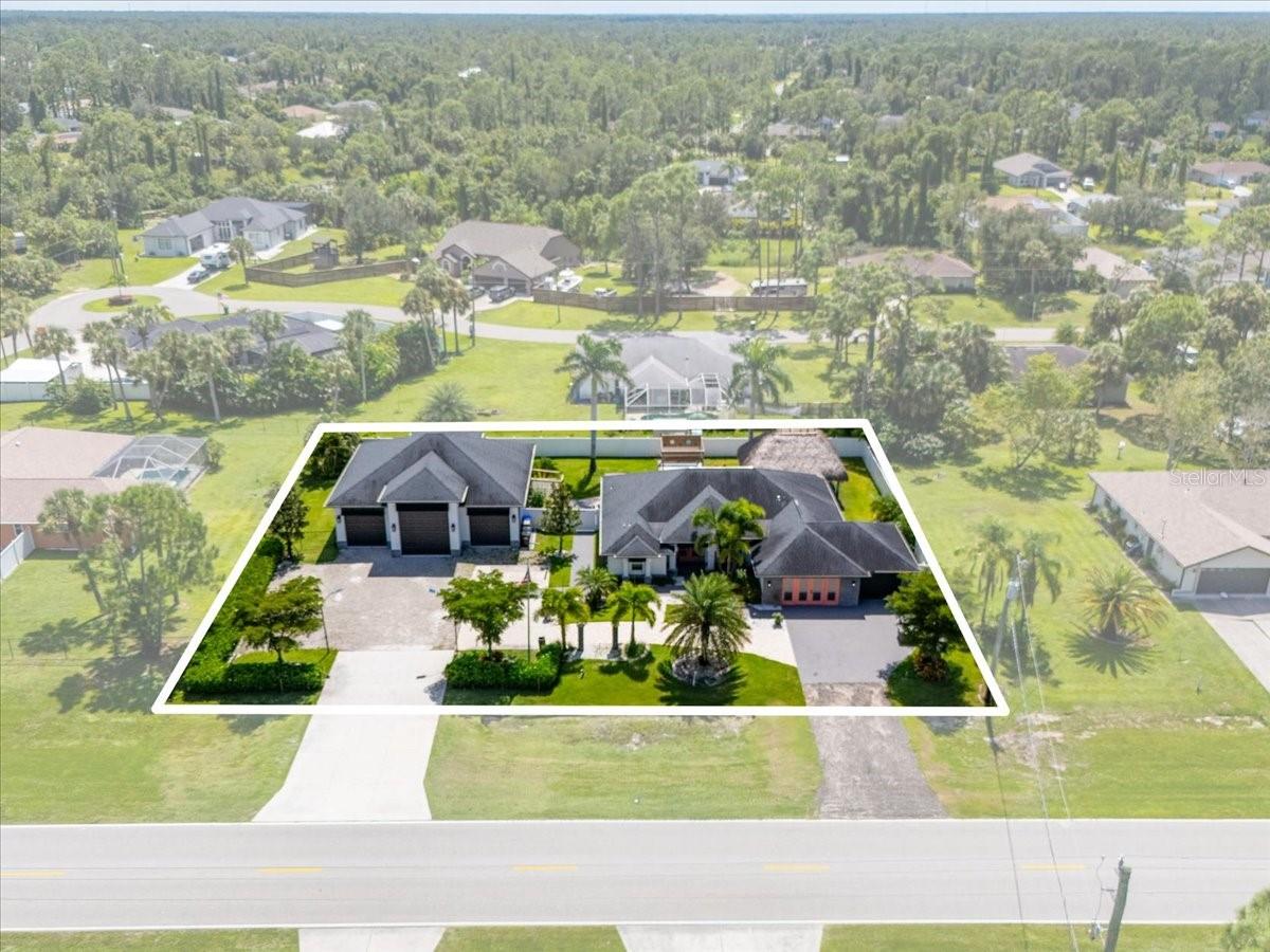 Step into luxury with this custom home built in 2018 by Walker Homes, offering 2,286 square feet of beautifully finished living space on an oversized half-acre lot in the heart of North Port. Featuring three bedrooms and two and a half baths, this thoughtfully designed residence boasts a split-bedroom layout with a spacious main-level primary suite, offering the perfect combination of comfort and privacy. The gourmet kitchen is a chef’s dream, highlighted by a striking waterfall island, custom cabinetry, stainless steel appliances, and high-end finishes throughout. The open-concept living space features coffered ceilings and is bathed in natural light, with durable luxury vinyl plank flooring throughout the main living areas and luxury tile in the bathrooms for a modern, cohesive feel. A bonus room off the main living area provides additional flexible space—ideal for a home office, playroom, den, or guest area—and includes extra built-in storage with endless potential to fit your lifestyle needs. Step outside into your private tropical retreat. Take a dip in the in-ground pool, grill under the expansive covered lanai with built-in summer kitchen or unwind beneath the brand-new patio pergola. A charming tiki hut adds a touch of island living—perfect for entertaining or simply relaxing in the shade. The lush landscaping is supported by an irrigation well system and enhanced by solar lighting, creating a tranquil, resort-style setting. The home also includes a finished RV port/garage wing with its own private entrance, workshop, office space, and half bath—perfect for guests, hobbies, or extended workspace. With plenty of parking for RVs, boats, or extra vehicles and no HOA or CDD fees, this home offers flexibility and freedom rarely found in a custom property.