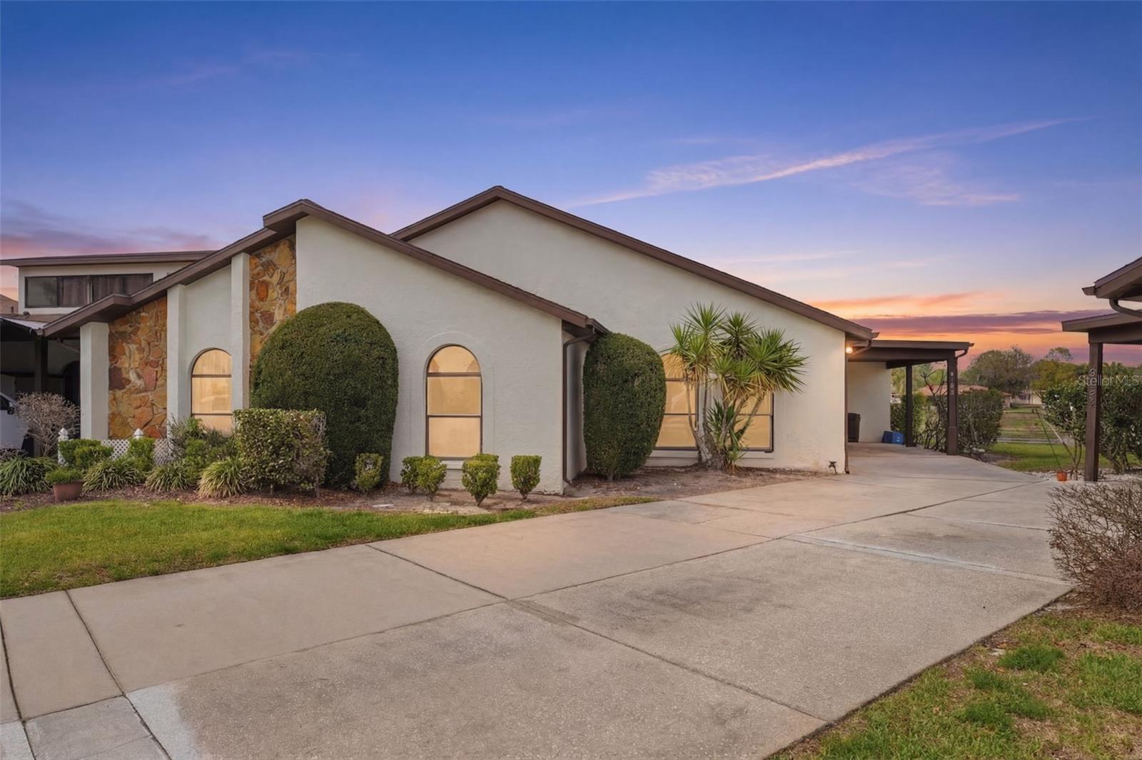 One or more photo(s) has been virtually staged. This charming bungalow-style villa is just as beautiful inside as it is outside, offering 3 bedrooms, 2 bathrooms, a Florida Room, and a single-car carport, all set against a peaceful backdrop of conservation views and a serene pond. Located in the desirable Heather Sound community, residents enjoy access to a community pool and hot tub, enhancing the relaxed Florida lifestyle. The carport features a decorative finished floor that adds a unique and polished touch, while the roof is only 6 years old for added peace of mind. As you enter through the foyer, you are welcomed into an open-concept layout that seamlessly blends the living room, dining area, and kitchen, with a convenient coat closet immediately to your right. The main living spaces are finished with wood-look luxury vinyl plank flooring, and the vaulted ceiling creates an airy, spacious feel. The living room features sliding glass doors that lead directly to the Florida Room, extending your living space and bringing in natural light. The kitchen is quaint and functional, offering white cabinetry, two windows, a ceiling fan, a double sink, and a nearby closet that serves as a laundry space with a stacked washer and dryer that convey with the home. The primary suite features clean, well-maintained carpeting, sliding glass doors that open to the Florida Room, and dual walk-in closets leading into the ensuite bathroom. The ensuite includes a step-in shower with grab bars and built-in shelving, a single vanity with white cabinetry, a wall-to-wall mirror, and vinyl flooring with a marble-like appearance. The second bedroom features two large windows that extend nearly to the floor along with well-maintained carpeting, while the guest bathroom offers a tub/shower combination, single vanity, wall-to-wall mirror, and matching marble-look vinyl flooring. The third bedroom also features well-kept carpeting, two built-in closets, and a large centered window that extends nearly to the floor, creating a bright and inviting space. The Florida Room is finished with tile flooring and provides a comfortable retreat to enjoy the outdoors year-round, offering beautiful views of the conservation area and pond directly behind the home while providing protection from the Florida elements. This home is located just down the road from Weeki Wachee Springs Park, a local attraction that features swimming, kayaking, water slides, and many other features right on the fresh water spring.