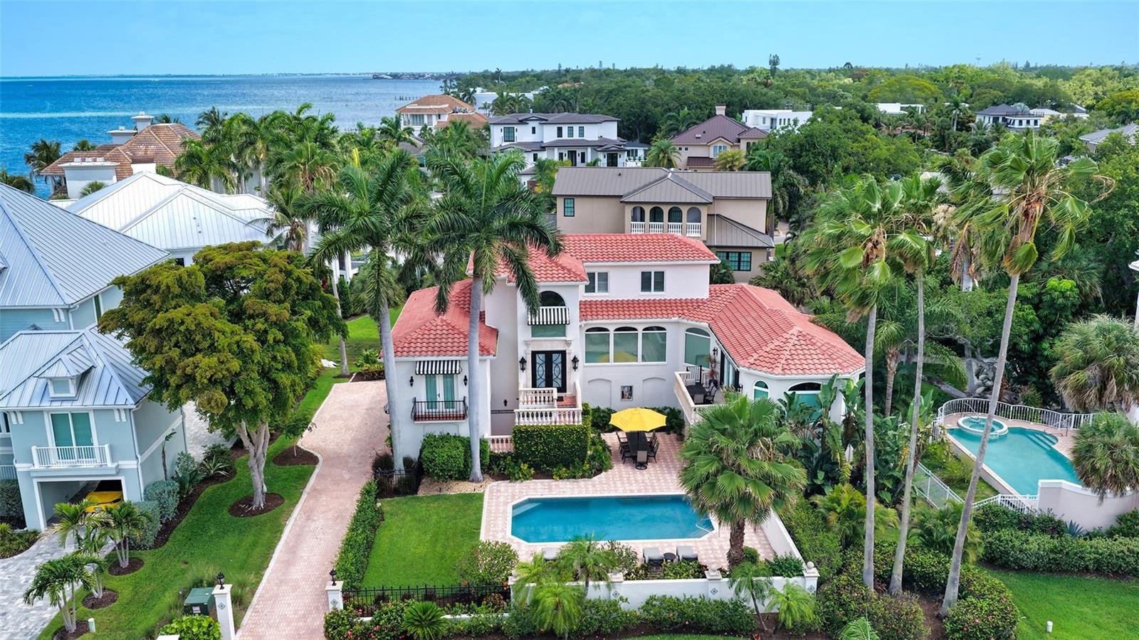 Sophisticated gated living just moments from the heart of downtown Sarasota. Evoking the timeless elegance of Palm Beach with the warmth of Old Florida charm, this exceptional Spanish Mediterranean residence is tucked within the exclusive gated waterfront enclave of Tocobaga Bay. One of only 9 private residences in the community, ideally positioned just moments from Sarasota’s renowned dining, arts, shopping, and waterfront attractions. Surrounded by lush tropical landscaping and tranquil water views, the home is thoughtfully designed for both sophisticated entertaining and relaxed everyday living. Expansive interiors are filled with natural light, highlighted by a grand foyer, travertine flooring, oversized floor-to-ceiling picture windows, motorized shades, and custom window treatments throughout. The residence features 3 bedrooms, each with its own ensuite bath, along with a media room or private office and a private 3-stop elevator. The oversized 4-car garage offers exceptional storage and ample space for vehicles, golf carts, kayaks, and recreational equipment, while the air-conditioned bonus room provides flexibility for a fitness studio, game room, private office, or additional storage. The newly renovated chef’s kitchen is beautifully appointed with premium finishes including a La Cornue gas cooktop, Sub-Zero refrigerator, custom Campbell Cabinetry, spacious walk-in pantry, oversized center island and Taj Mahal quartz countertops and backsplash. The oversized living room offers an inviting atmosphere for gathering, while the separate formal dining room is perfectly suited for elegant dinners and entertaining. The primary suite serves as a peaceful sanctuary complete with its own Juliette balcony, dual custom walk-in closets, and a spacious ensuite bath. Two additional guest suites occupy the third floor, each with private baths, offering ideal comfort and separation for family and guest. Designed to embrace Sarasota’s indoor-outdoor lifestyle, the open-air heated saltwater pool is surrounded by lush tropical landscaping and expansive patio space for lounging and dining. Additional improvements: new tile roof (2023), new irrigation system (2024), updated water heaters (2023 & 2024), electrical panels (2024), and updated A/C units. Residents enjoy access to the community day dock with direct bay access, perfect for boating and waterfront enjoyment. Perfectly located near Sarasota’s renowned beaches, St. Armands Circle, The Bay Park, and the iconic Ringling Bridge, this remarkable residence offers an exceptional lifestyle just minutes from the energy and culture of downtown Sarasota. Offered fully furnished and ready for immediate enjoyment.