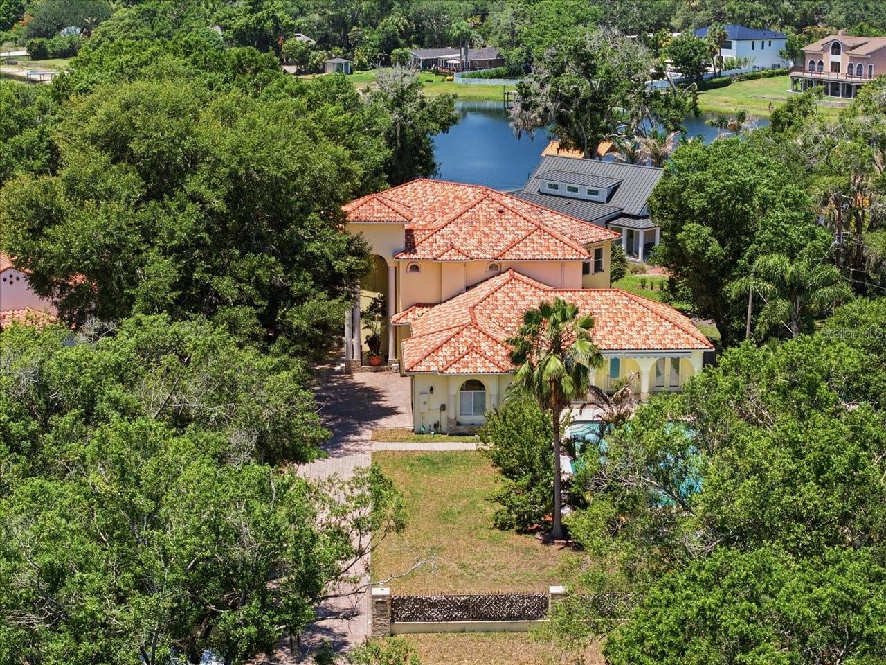 Nestled along the shores of Lake Carroll, this extraordinary waterfront estate captures sweeping open views across the 210-acre ski lake from a rare ¾-acre all-dry lot, offering an exceptional combination of luxury, privacy, and convenience. Perfectly positioned on a peaceful cove with easy access to Carrollwood amenities and downtown Tampa activities, this remarkable residence delivers resort-style living with breathtaking water views at every turn.
Featuring 6 bedrooms, 4.5 baths, and thoughtfully designed living spaces, the home is perfectly suited for both elegant entertaining and everyday comfort. At the heart of the home is a spacious gourmet kitchen featuring a center island, breakfast bar, pantry, and abundant cabinetry, seamlessly opening to the expansive family room adorned with beautiful coffered ceilings, creating an inviting gathering space while showcasing spectacular lake vistas.
Designed with flexibility in mind, the main level features two bedrooms connected by a Jack-and-Jill bath, along with a private entrance and kitchenette, creating an ideal setup for an in-law suite, guest quarters, private apartment, or multigenerational living arrangement.
Upstairs, you'll find four additional bedrooms, including the impressive primary suite complete with a private balcony overlooking the lake, creating a peaceful retreat with panoramic waterfront views.
Convenience abounds with two laundry rooms—one on each level—providing added functionality for busy households and guests alike.
Outdoor living is nothing short of spectacular with a sparkling pool, expansive elevated rear patio designed to maximize the stunning open-water views, and a covered boat dock with lift providing direct access to boating, fishing, watersports, and unforgettable sunset cruises on Lake Carroll.
This one-of-a-kind waterfront estate combines an oversized all-dry homesite, expansive open-water views, versatile living spaces, and an unbeatable location into an extraordinary lifestyle opportunity.