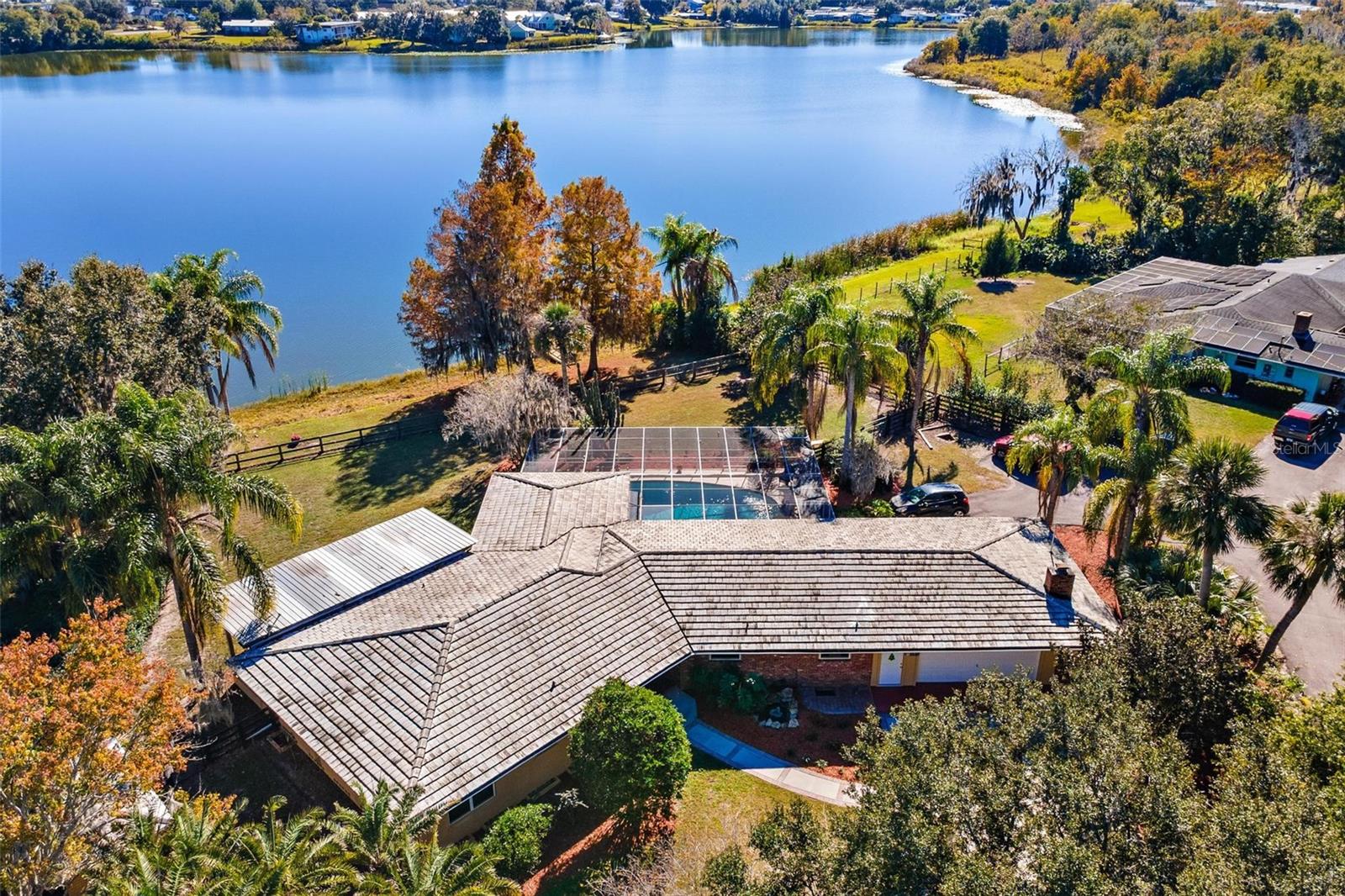 This MID-CENTURY MODERN brick home offers TIMELESS CHARACTER and STYLE of LAKEFRONT LIVING set on .97 ACRE with 145 feet on Lake Enola in Umatilla. Built in 1954, carefully designed to capture lake, pool, and outdoor VIEWS from nearly every room.  ORIGINAL recently refinished WOOD FLOORS, abundant windows with wood blinds and OVERSIZED hurricane resistant sliding glass doors fill the home with natural light and breathtaking scenes. The layout is well suited for entertaining or quiet mornings with coffee on the back deck or inside the screened pool area. The kitchen features granite counters, wood cabinetry, and stainless-steel appliances. An indoor utility room includes inside laundry, a utility sink, and a spacious pantry leading to the air conditioned 2 1/2 car garage. The fully fenced LAKEFRONT BACKYARD offers BASS fishing from your DOCK, blooming AZALEAS, hibiscus, gardenia and magnolia; a generous space for gardening or outdoor enjoyment. Additional features include the garage half bath, CONCRETE ROOF TILES, a 100-sq-ft workshop/storage building, 200-amp electrical service with updated panels, a one-year American Home Shield Home Essentials Warranty provided by the seller, city water and sewer. The property offers a peaceful, country feel while remaining within walking distance to downtown Umatilla. HVAC 2020, electrical 2015. About 20 min to The Villages to the west or the Lake County expressway extension to the southeast.  By Appointment only – so Call to make one!