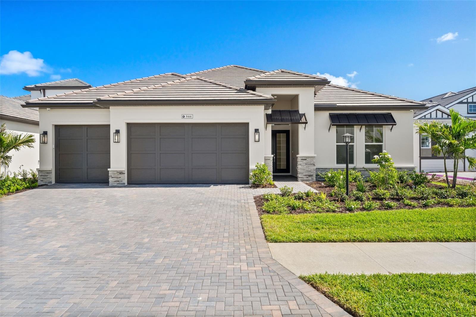 Virtually Staged. Experience exceptional waterfront living in this newly completed Outrigger Model from Homes by Towne, this modern mediterranean inspired design is ideally situated on a premium lakefront
homesite in Shellstone. Designed for both elegant entertaining and everyday comfort,
this move-in ready residence showcases breathtaking water views and upgraded
finishes throughout, including double door entryway, tray ceilings, modern carpet free
oversized porcelain tile floors, upgraded cabinetry with under cabinet LED lighting,
counter to ceiling decorative tile, Calcutta quartz countertops, a GE Monogram appliance suite including a
thirty-six inch gas cooktop and Advantium oven. Round your chef's kitchen out with a dedicated sommelier’s station and
dry bar. After the cooking is done, enjoy your breakfast in the custom Good Morning Room with expansive lake views. The Great Room showcases a striking
modern electric fireplace with a floor to ceiling tile surround and mirrors. The modern
open concept floor plan flows seamlessly to an expansive Lanai. Once outside you will notice upgraded pavers, an optional pool
bath upgrade, summer kitchen rough-ins, all surrounding the crown jewel of your oasis a stunning Pebble Tec saltwater pool with sun
shelf, water features, and panoramic screened lake views. Built for energy efficiency and peace
of mind your new home includes hurricane-impact glass windows and doors, spray foam
insulation, tankless gas water heater, 4-camera CCTV security system all providing security and safety for the whole family. Additional features include a 3 car garage with
upgraded polyaspartic coated floor, EV charging station, generator ready gas lines,
pre-plumbing for a whole home water softener system, enhanced landscaping, and
additional designer touches throughout. Residents enjoy access to Shellstone’s resort
style amenities, including a private clubhouse with pool and spa, state-of-the art Fitness
Center, Fitness lawn, tennis and pickleball courts, walking/jogging trails, kayak launch
and dog parks- all minutes away from downtown Sarasota, the Waterside Shops,
University Town Center, waterfront dining, and pristine Gulf Coast beaches. Is this home
your perfect match?!