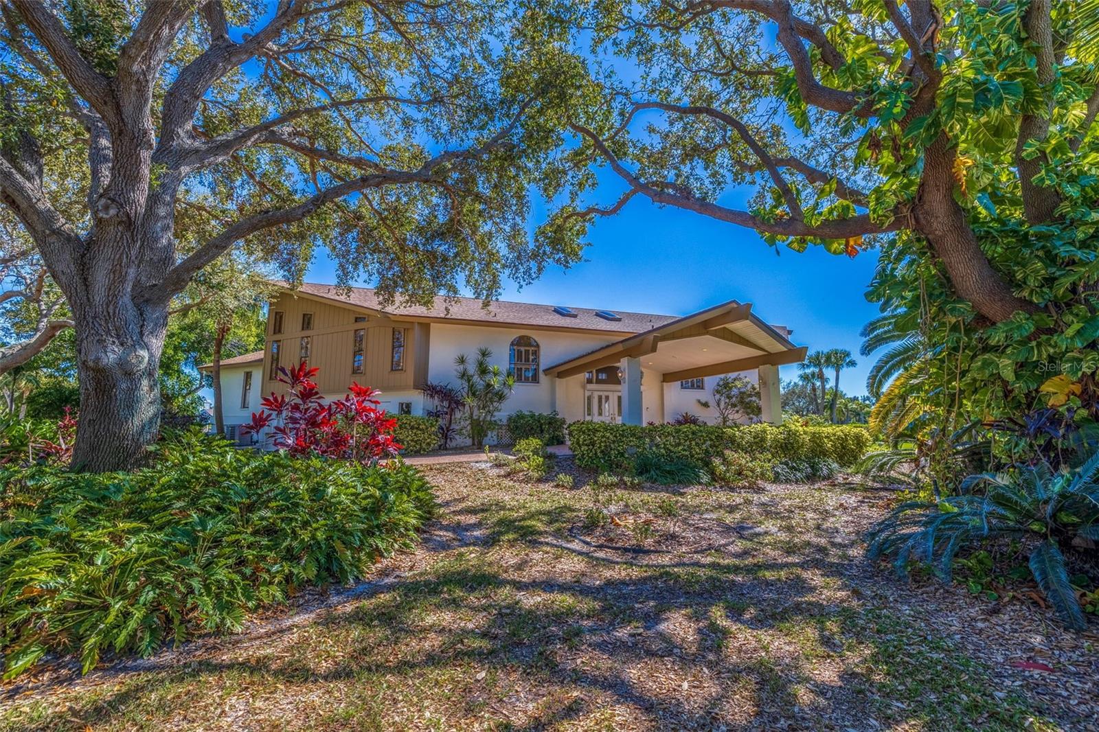 Dreaming of the Florida lifestyle? Relax and retreat to this one-of-a kind ELEVATED, WATERFRONT home on the sought after island of Tierra Verde. Situated on a sprawling corner lot surrounded by lush landscaping sits this Swedish Long House style home, which was originally custom built for the musical group ABBA.  It features a paved, circular driveway with a grand porte-cochere. Step into the home where you are greeted by a bright, sky-lite foyer that opens to the spacious great room with soaring ceiling, a floor to ceiling imported stone, gas fireplace and views of the salt-water canal. Offers 4,527 sq. ft. of living space with 6-bedrooms and 4 bathrooms plus 2 half baths. It has a unique design as it is divided into two identical “Mirrored” floor plans that branch off the large great room so that quests or family can retreat to their own living space. Each side includes: a first-floor master suite with an ensuite bathroom with a jacuzzi tub and walk in closet, a second-floor loft area and two bedrooms with a Jack-and-Jill bathroom. The large covered deck with a hot tub overlooks the salt water canal, heated in-ground pool with paved deck and the Trex boat dock. Both sides have a 2-2 garage with separate entrances and abundance of storage capacity. Recent upgrades include a new roof, skylights, battery ready solar panels, three zone HVAC system, and fresh paint inside and out. 2 new Rheem HYBRID 50 gallon water heaters-most efficient electric/solar heat pump water heaters. The windows and sliders are hurricane protected with electric shutters (entire back of house) or plexiglass (front windows). Located only 30-40 minutes from 2 international airports via I-275, 5 minutes to the Sunshine Bridge,10 minutes to downtown St. Petersburg with its cultural attractions, entertainment, and fabulous restaurants. 5 minutes to award winning St. Pete Beach and Fort DeSoto – an 1100 acre park offers sugar sand beaches, camping, kayaking and miles of nature trails – is right in our backyard. AND miles of trails!