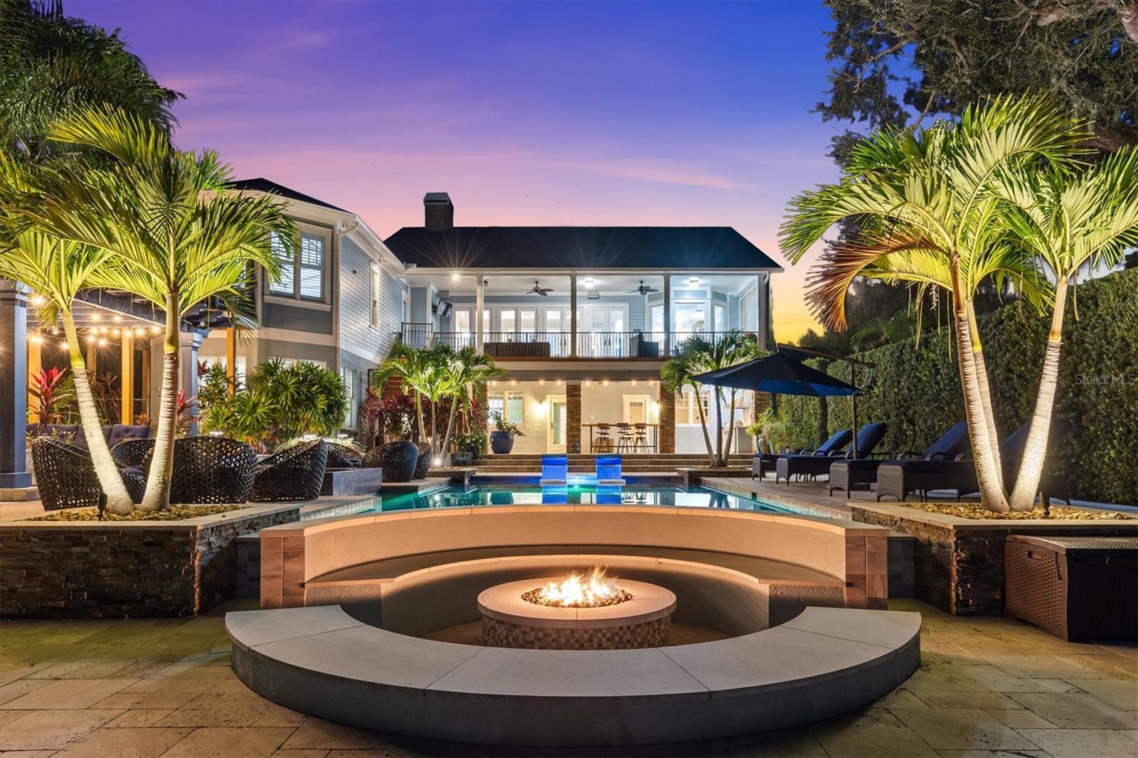Inspired Waterfront Living on Lake Tarpon Discover this stunning 7,682 SF estate which includes a full guest apartment on nearly one acre offering breathtaking views of the 2,500-acre Lake Tarpon. Gated for privacy, it features a private dock with 10,000-lb boat lift for sunset cruises, fishing, or kayaking, all with no HOA fees or flood insurance required. Nestled in the prestigious Palm Harbor University school zone, this move-in-ready haven combines serene lakefront allure with sophisticated luxury for discerning buyers. Over $400K invested in a "backyard nirvana" by acclaimed designer Ryan Hughes creates an unparalleled outdoor oasis: resort-style pool with ledge loungers, glistening tiled infinity-edge spa, sunken fire lounge, charming pergola, cozy moon daybed for stargazing, and dramatic custom lighting blending light, water, and fire across travertine decking amid stately grandfather oaks and vibrant tropical landscaping. The extensive covered lanai seamlessly connects to indoor spaces, ideal for gatherings, while the open floor plan greets with immediate lake views through walls of glass in the expansive family room, accented by a fireplace and decorative tray ceiling.
Inside, the chef's kitchen shines with quartzite island and granite countertops, custom cabinetry, Wolf commercial gas range, SubZero appliances, double ovens, walk-in pantry, and casual dining. The main-level owner's retreat boasts a beamed vaulted ceiling, serene lake views, dual closets, and spa bath with jetted tub and shower. Lower-level entertainment includes a bonus room with full wet bar, home theater, home gym, extra storage, three bedrooms, two baths, new tile, 2nd laundry room and lots of storage—plus a separate in-law suite with full kitchen, living/dining, and laundry. Recent updates feature a brand-new roof (2025), five AC units replaced since 2019, 3 tankless water heaters, whole-home water softener/filtration, fresh paint, extended driveway, Generator, dedicated podcast room, and tech-savvy amenities like WiFi 6, Sonos audio, Mohen AI leak detection, integrated security, and smart locks. Accessed via gated cobblestone entry to a spacious motor court and Trex-decked porch, this unmatched property redefines waterfront sophistication.