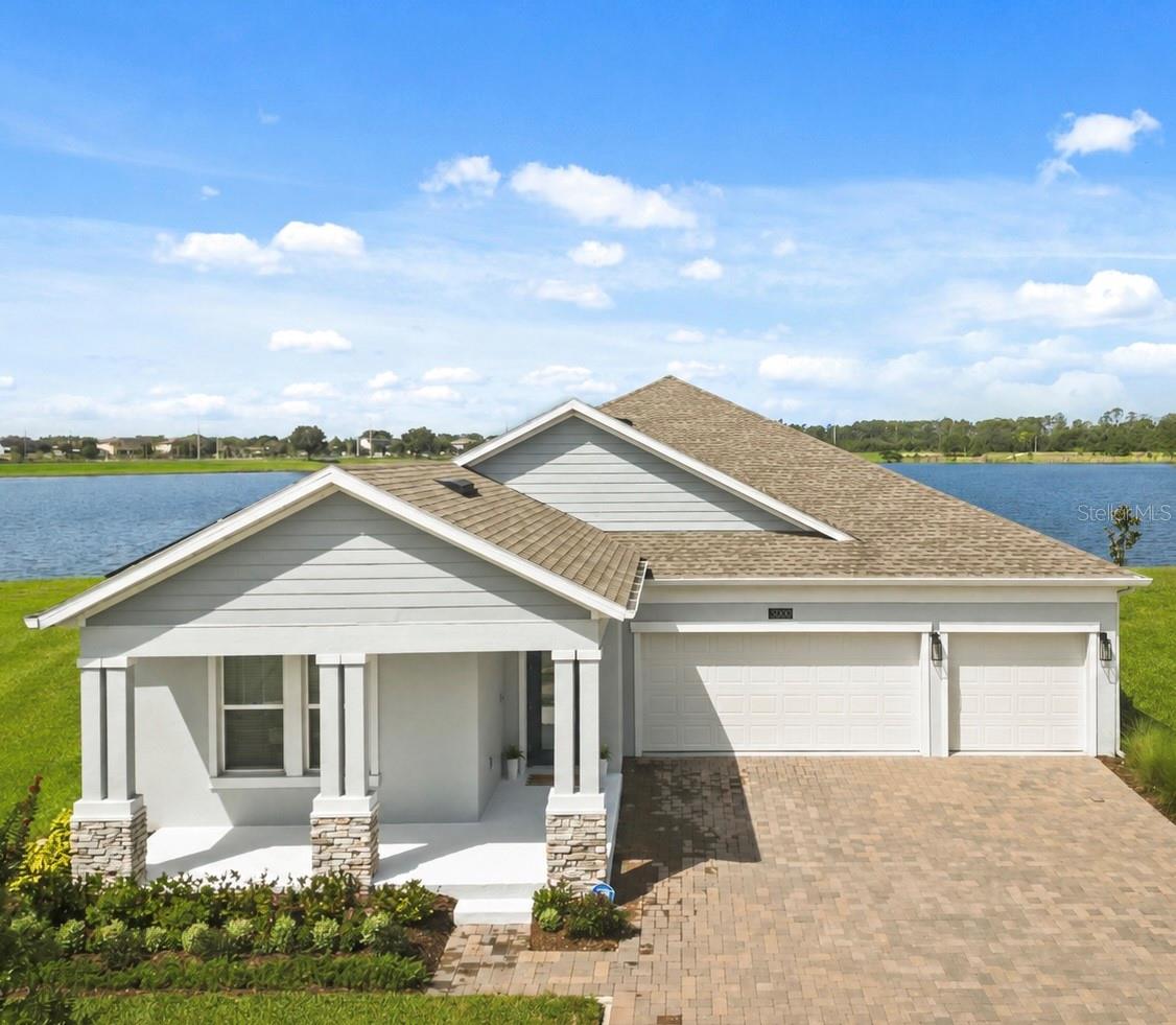 Welcome to one of the most exceptional homes in Bridgewalk, situated on the community's largest waterfront homesite, offering breathtaking sunset views from nearly every rear-facing room. Built in 2022, this beautifully designed residence features 4 bedrooms, 3 full bathrooms, over 2,600 square feet of thoughtfully planned living space, and an oversized 3-car garage. The open-concept floor plan is filled with natural light and showcases spacious living areas, generously sized bedrooms, and an office/great room, providing flexibility for today's lifestyle. Elegant tile flooring extends throughout the entire home, creating a seamless and low-maintenance living environment. The well-appointed kitchen opens to the dining and great room, making it ideal for both everyday living and entertaining. Step outside to enjoy the covered lanai overlooking the tranquil water, where you'll experience spectacular sunset views and peaceful outdoor living. The covered front porch adds to the home's inviting curb appeal, complemented by easily maintained landscaping and exceptional lot placement. Additional features include a whole-home water filtration system and a solar panel lease that will transfer to the buyer at closing, offering enhanced efficiency and long-term value. Bridgewalk residents enjoy an impressive collection of resort-style amenities, including a community pool, fitness center, playground, parks, racquetball courts, scenic walking and biking trails, and a community boat launch with water access. Ideally located in the highly desirable Sunbridge area just minutes from Lake Nona, this home offers convenient access to Medical City, Orlando International Airport, major highways, shopping, dining, and the area's continued growth and development. Combining an outstanding homesite, modern construction, exceptional amenities, and an unbeatable location, this is a rare opportunity to own one of Bridgewalk's premier waterfront properties.