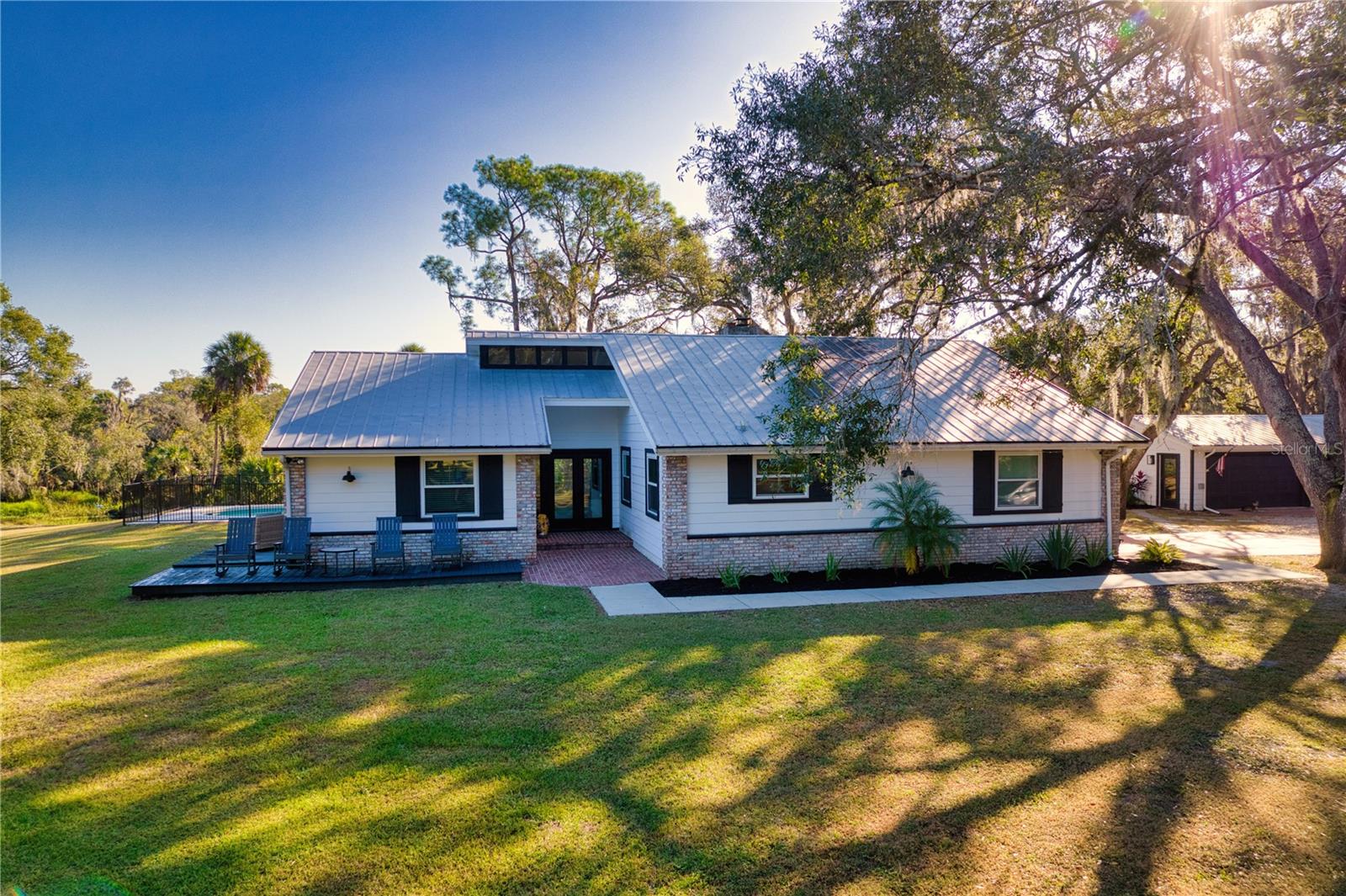 A rare opportunity to own 5 AG-zoned acres with direct frontage on beautiful Gamble Creek—all with no HOA or CDD! This private country retreat offers the perfect blend of peaceful living, outdoor recreation, and income-producing potential. The AG zoning provides exceptional flexibility for agricultural uses, livestock, hobby farming, and a variety of rural lifestyle opportunities.
The thoughtfully updated 3-bedroom, 2-bath modern farmhouse offers more than 2,100 square feet of living space with soaring ceilings, abundant natural light, two wood-burning brick fireplaces, luxury vinyl plank flooring, and Anderson French doors that open to the pool and outdoor entertaining area.
The beautifully renovated kitchen features quartz countertops, a farmhouse sink, subway tile backsplash, and newer stainless steel appliances. A spacious 320-square-foot mudroom provides exceptional flexibility as a home office, hobby room, fitness space, storage area, or potential fourth bedroom.
Adding tremendous value is the fully converted 740-square-foot guest home (ADU) with its own private entrance. Complete with a full kitchen, living area, bedroom, full bathroom, and laundry, it's ideal for short-term rental income, extended family living, guests, or a private home office/workspace.
Step outside and discover everything this unique property has to offer. Enjoy direct access to Gamble Creek for kayaking, paddleboarding, and fishing. The property also includes an RV or tiny home pad with electric, water, and septic hookups,  a covered pole barn, and sprawling open acreage shaded by majestic oak trees.
Whether you're envisioning a hobby farm, equestrian estate, workshop, event venue, multigenerational living, or simply a peaceful private retreat, this versatile property is ready to bring your vision to life.
Recent improvements include impact-rated windows and doors, luxury vinyl plank flooring, an updated electrical panel, newer stainless steel appliances in both the main home and ADU, a new pool pump, water heater, drain field, well filtration system, and numerous additional upgrades—providing peace of mind for years to come.
Waterfront acreage, income potential, versatile outbuildings, and unmatched privacy make this truly a one-of-a-kind opportunity. Schedule your private showing today and experience everything this exceptional property has to offer.