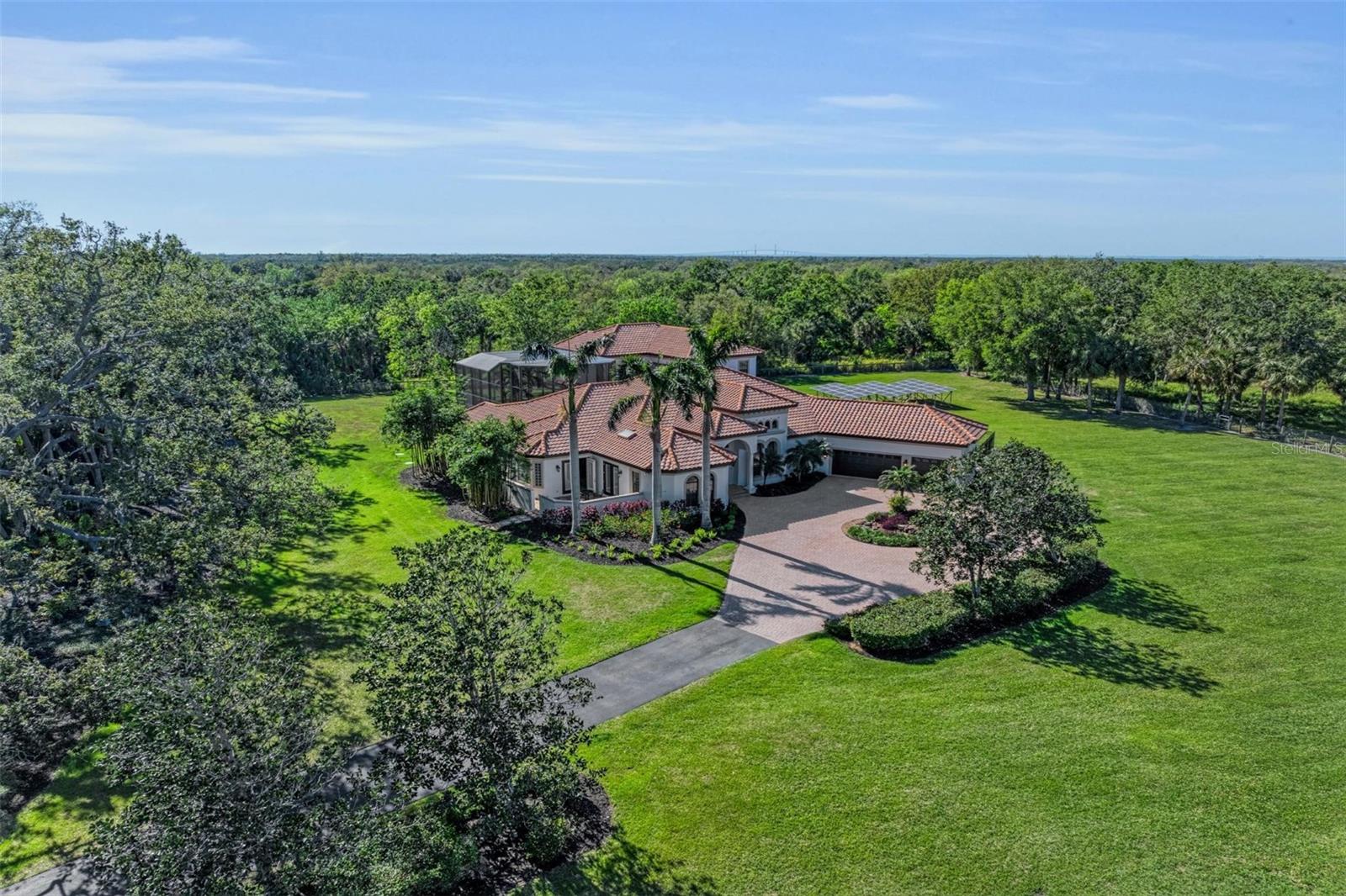 Welcome to this extraordinary custom-built John Cannon estate, where seclusion, luxury, and modern convenience merge flawlessly. Located just minutes from I-75 and I-275, and five minutes from the rapidly growing North River Ranch with brand-new schools, medical facilities, restaurants, and more, this lovely 5 acre masterpiece is sure to impress with 4 bedrooms, 4.5 bathrooms! The perfect blend of elegance and practicality with the freedom that comes from NO HOA or CDD. Freshly painted interior and exterior, along with energy-efficient features like a modern tankless water heater and ground-mounted solar panels, ensure comfort and sustainability. The open floor plan is perfect for both relaxing and entertaining. The gourmet kitchen with sub-zero and induction stove flows seamlessly into the expansive great room and dinette, perfect for hosting guests. Enjoy added luxury with a soundproof theater room, a library with built-in bookcases, and BONUS ROOM or a possible 5th bedroom. Outdoors, the tropical entertainment area with salt water pool and spa, offers the ultimate in privacy and relaxation. Fenced dog yard with synthetic grass, lush landscaping including majestic oaks and a statue garden are just a few extras. Nature lovers will delight in the adjacent 2,000-acre Terra Ceia State Preserve, perfect for birding, fishing, and hiking, while horse lovers will enjoy the world-class equestrian facility offering programs for riders of all ages nearby. The easy access to St. Petersburg, Tampa, Orlando and Sarasota makes this the ideal location on the gulf coast. This is more than just a home - it’s a lifestyle, where every day feels like a vacation. With OWNER FINANCING available, don’t miss your chance to own a piece of Florida’s finest real estate. Live the dream today!