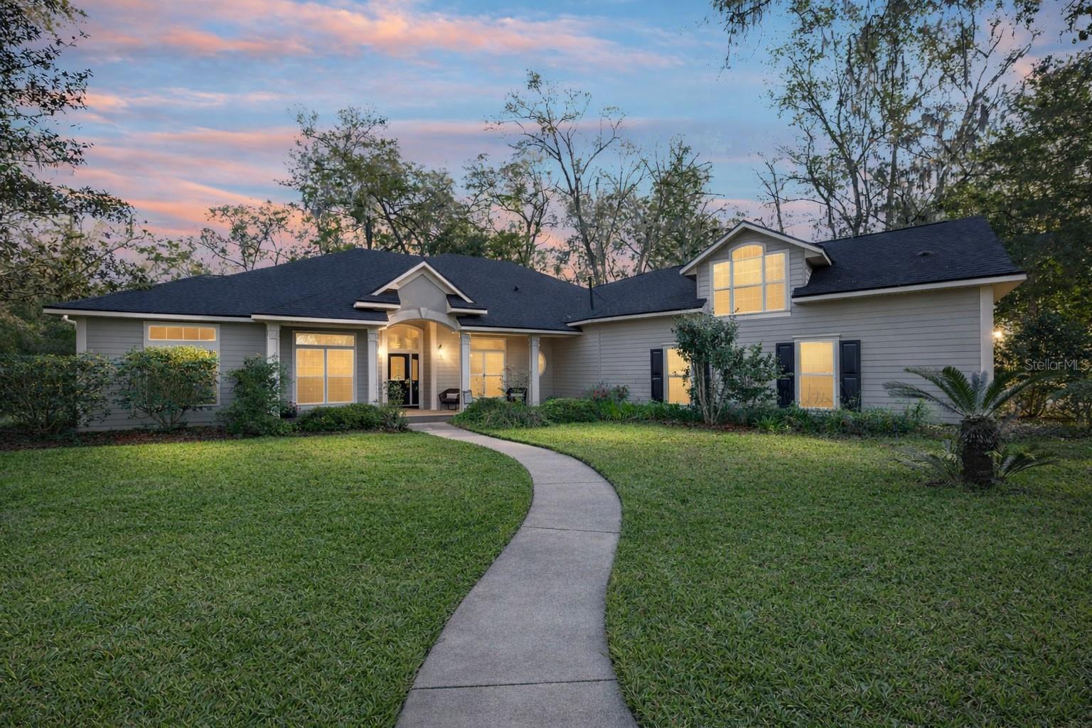 One or more photo(s) has been virtually staged. HUGE Price Improvement!  Situated within the gated Steeplechase Farms community, this 5-bedroom, 3 full and 2 half-bath custom home offers over 4,100 square feet of living space on 1.78 private acres. Major updates have already been completed, including a new roof (2024), HVAC (2021), and water heater (2020), providing added peace of mind. The interior features high ceilings, a stone-accented fireplace, and open living and dining areas, along with a spacious kitchen offering a large island, pantry, and ample prep space. The main-level primary suite includes direct pool access, dual closets, and a generous en-suite bath, while three additional bedrooms and an upstairs suite provide flexible living options for guests or multi-generational needs. Outdoors, enjoy a screen-enclosed pool with an extended deck and covered lanai, all set on a fully fenced lot shaded by mature oaks with no rear neighbors. A circular paved driveway and side-entry three-car garage add both function and curb appeal, all just minutes from Newberry, Tioga, Publix, and UF/Shands.