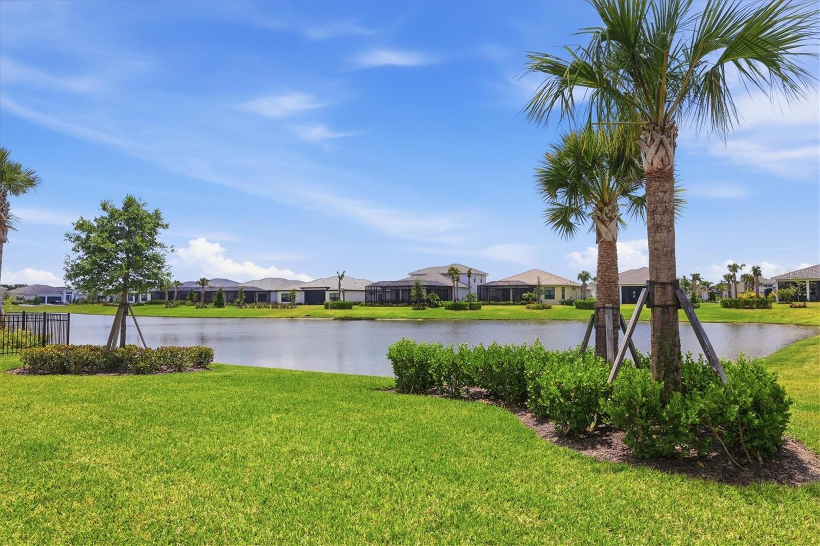 Virtually Staged. Welcome to Artistry–Sarasota, where you can experience luxurious resort-style amenities, maintenance-free living and easy access to Lakewood Ranch and Waterside, without the CDD fees. This beautifully designed Van Gogh model offers one of the most desirable floor plans available in Artistry. From the moment you enter through the large, double-door entry, you’re immediately welcomed by a spacious foyer with an architectural ceiling and views through the home to the tranquil water beyond. The 12-foot ceilings, generous living areas and abundant natural light will surround you with a sense of serene openness. Practically everything in this home has been upgraded with a focus on minimalist modernism. The large-format tile floors throughout provide elegant texture both physically and visually. The custom cabinetry provides a sleek, uncluttered environment in the spacious kitchen and pristine baths. Calacatta Izaro premium quartz countertops and Hansgrohe and Delta fixtures are featured in each of these areas. The open modern kitchen features a gas cooktop, dual wall ovens and Bosch appliances. Even the 7-inch baseboards, custom 8-foot doors and oversized interior trim are thoughtful upgrades by the homeowners. Reach out for the detailed feature sheet with the lengthy list of features and upgrades. This refined residence provides an optimized, split floor plan that maximizes function and privacy with three bedrooms and baths (two are en suites) located at the corners of the home. The primary suite, positioned at the back of the residence, offers a wonderful respite with water views and evening sunsets. The spacious spa-like bath invites with floor-to-ceiling tile, floating custom vanities, multi-control shower fixtures, a private lavatory and a large walk-in closet. The other baths are similarly appointed with luxury features and privacy. The large flex space adjacent to the great room and kitchen provides lifestyle options: a study for work-from-home, a potential theater/media room or even a large formal dining room, to name a few. The large great room is the center of the home and perfect for relaxing or entertaining family and friends. And, when it’s time for a bit of fresh air, the two sets of triple sliding glass doors will lead you to an extended lanai and beautiful backyard overlooking the water. Even this generously sized area was thoughtfully planned with plumbing and power for an outdoor kitchen and pool. Equally important to all that makes this residence special is what makes it exceptionally safe and energy efficient: impact windows and doors, concrete block construction, a concrete tile roof, spray foam insulation, natural gas utilities and new fiber-optic internet. Community features and amenities include two gated entrances, a huge pool, a clubhouse, tennis and pickleball courts, a playground area and a fitness center, all surrounded by tranquil, landscaped walking paths. Artistry is a maintenance-free, upscale community with no CDD fees, convenient to just about everything that makes Sarasota and Lakewood Ranch desirable, particularly the shopping, dining, entertainment, excellent schools and our destination beaches. There is an art to living well, and you’ll find it here in Artistry-Sarasota!