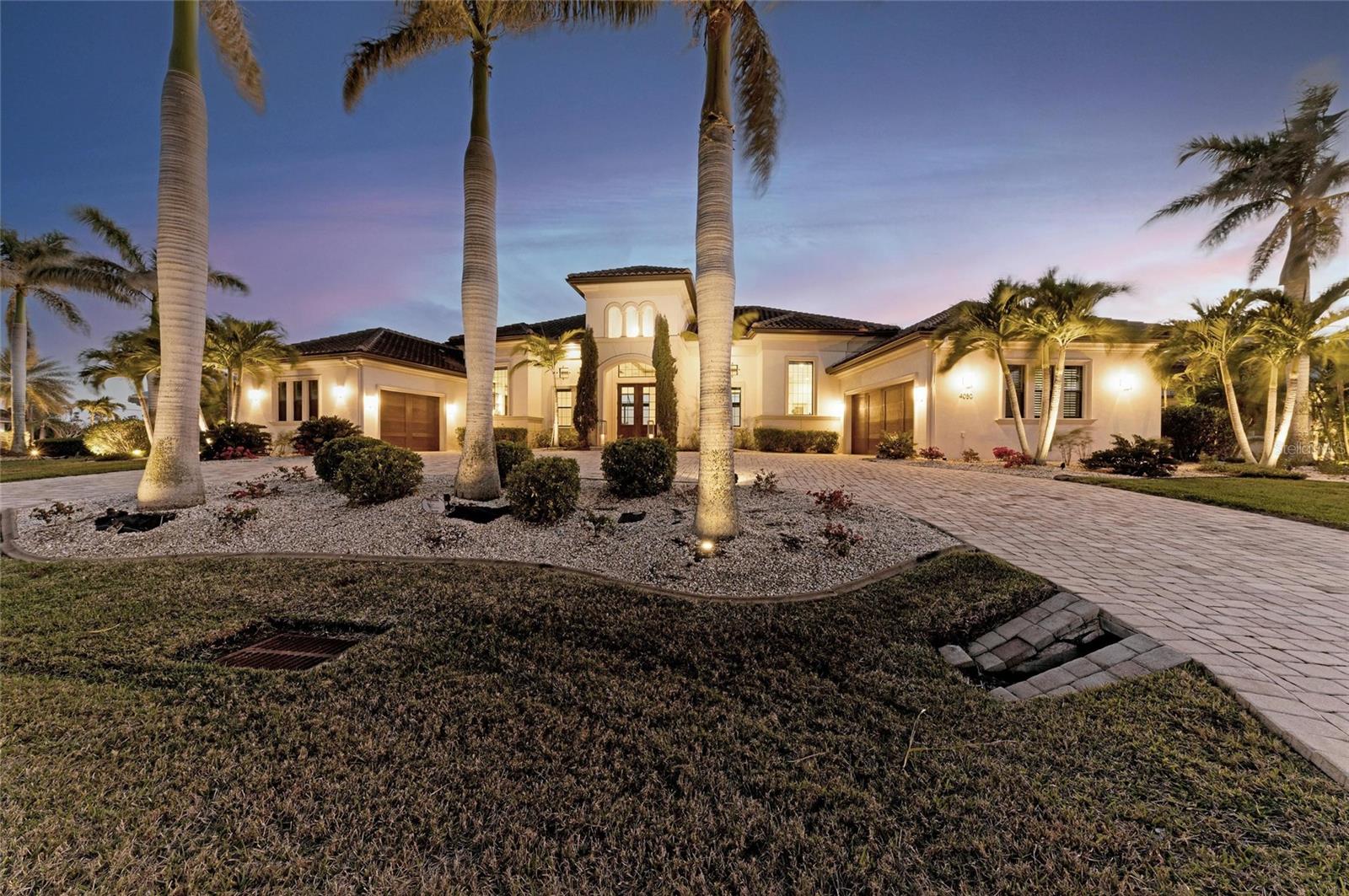 INCREDIBLE Contemporary 2016 Built Custom Waterfront Pool Home with SOUTHWEST EXPOSURE & LONG WATER VIEWS on 2 LOTS ON THE WIDEST/LONGEST DEEP-WATER SAILBOAT ACCESS CANAL with 90' Dock & 10,000lb lift being sold TURNKEY FURNISHED SEPARATELY (ALL Restoration Hardware brand) awaits new owners! This stunning nearly 1/2 acre lot boasts a custom Arthur Rutenberg single level home built to 12' elevation with a large circular driveway and 2 side loading oversized garages, along with upgraded landscaping including mature palm trees and lighting, and a stately entryway. Inside the double doors, find yourself captivated by the grand entryway with reflection pool that opens into the main living/dining/kitchen areas all open and overlooking the incredible long water views and beautiful pool/spa outdoor areas. Notice French patterned travertine flooring throughout the entire home and also find Shellstone travertine on the entire lanai. The natural stone walls inside are repeated cleanly for architectural detail, as is the dark stained oak trim work including custom feature wall and bookshelves built in throughout the home. Keeping in line with the clean, contemporary look, find Cambria quartz counters throughout and custom cabinetry, as well. Notice the fantastic layout with an masive great room open to the gourmet kitchen with excellent counter space/storage, GE Monogram appliances, a large hidden pantry, large center island with waterfall countertops, and massive dining area, all designed for the bespoke furniture. The entire back of the main living areas opens up with 10' pocket sliding glass doors in the living/dining areas. Divided into two wings, the East wing holds a power room, a large office with French doors to the lanai, and 2 guest suites, each with large closets and en suite bathrooms. Also on this side is a entry hallway with built in shelving and access to one of the garages. The West Wing, on the Kitchen side of the home has a spacious laundry room with technology closet, access to the larger garage, and another guest bedroom and separate bathroom.  The primary suite is beautiful and spacious, with a massive walk-in closet with built in organization, a spa-like bathroom with separate jetted free-standing tub, shower, dual vanities, direct access to the lanai and private seating area, and a spacious bedroom with sitting area and lanai access.  Outside on the lanai, enjoy beautiful sweeping views and many great places to relax including a covered dining area with built in summer kitchen, a sundeck space, and two additional covered seating areas, all within the lanai with a massive panoramic pool cage.  Outside, an additional sundeck awaits on the way to the oversized dock. This is a 15-minute boat ride with no bridges to Charlotte Harbor and the Gulf beyond! Don't forget the City of Punta Gorda maintains the concrete seawalls and depths of the canals, too! The exposure of this home and construction allows for year-round comfort with buffered protection from the Northern winds and enjoys lovely sunsets! Be sure to ask for the feature sheet that includes additional details such as spray foam insulation in the whole home, impact windows & double insulated glass sliding doors with accordion shutters, a large summer kitchen on the lanai, and more! Schedule your showing today to make this captivating home yours! BE SURE TO CLICK THE FULL VIRTUAL TOUR LINKS FOR DETAILS