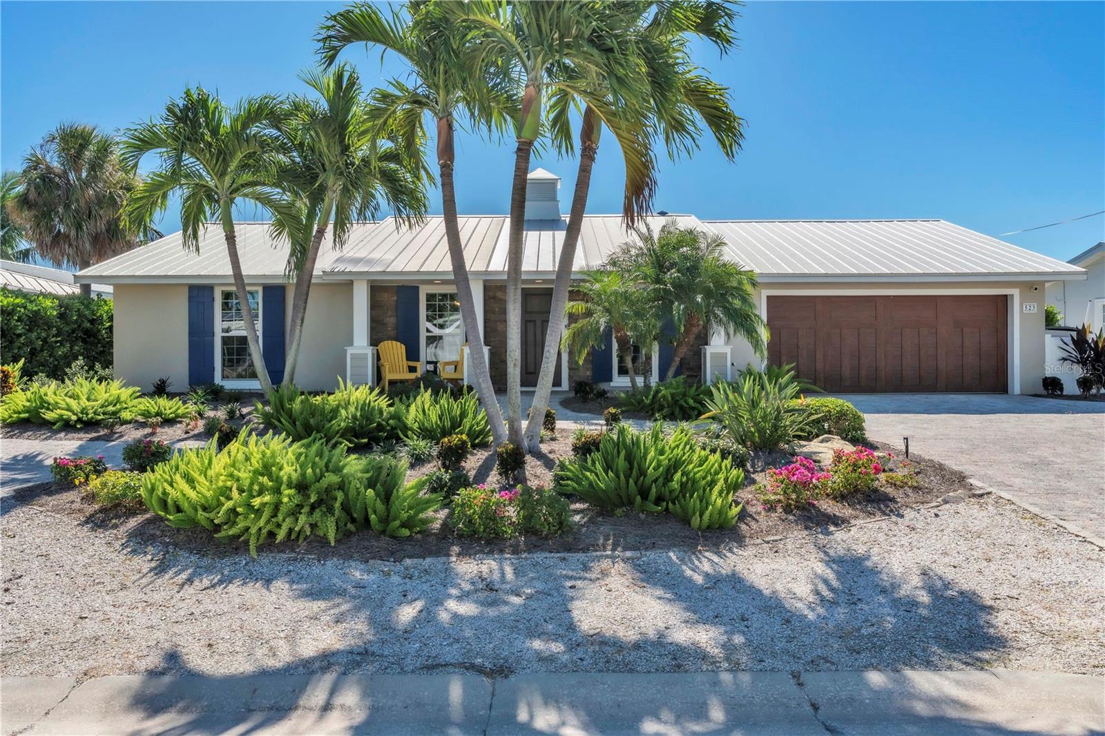 Effortlessly blending relaxed coastal living with refined design, this beautifully remodeled 3BD/3BA retreat invites you to slow down and stay awhile. Inside, the heart of the home is a show stopping kitchen that exceeds expectations with wood cabinetry, sleek quartz counters, a gas range, double ovens, wet bar with wine fridges, and a massive center island that makes entertaining both elegant and easy. Rich wood beams warm the open concept living and dining areas, where natural light spills in through oversized sliders that frame the view to your private outdoor oasis. Two of the bedrooms feature ensuite bathrooms, offering comfort and privacy for guests or family. The seamless indoor outdoor flow leads to a backyard paradise designed for total enjoyment, with a sparkling heated pool and spa, lush tropical landscaping, and ample space for lounging in the sun or shade. A private dock with electric and water access extends your lifestyle to the water, whether you’re an avid boater or simply enjoy the waterfront setting. Under the covered outdoor living space, complete with grill, refrigerator, and a wood burning fireplace with updated gas components (December 2025), the space transforms into the perfect spot for gathering year round. Thoughtful upgrades throughout include the full replacement of all original cast iron plumbing, removal of all in floor water lines and installation of new water lines in the attic, all new electrical wiring, fixtures, and panel, plus an on demand hot water heater with a recirculating pump delivering instant hot water to every sink and shower. A buried 125 gallon propane tank supports the gas features throughout. Topped with a durable metal roof and fortified with impact rated windows and doors, this canal front gem is as solid as it is stylish. Just a short stroll or bike ride to the sugar white sands of Anna Maria Island and moments from beloved shops, restaurants, and local attractions, this is island living perfected, don’t let this rare coastal escape slip away.