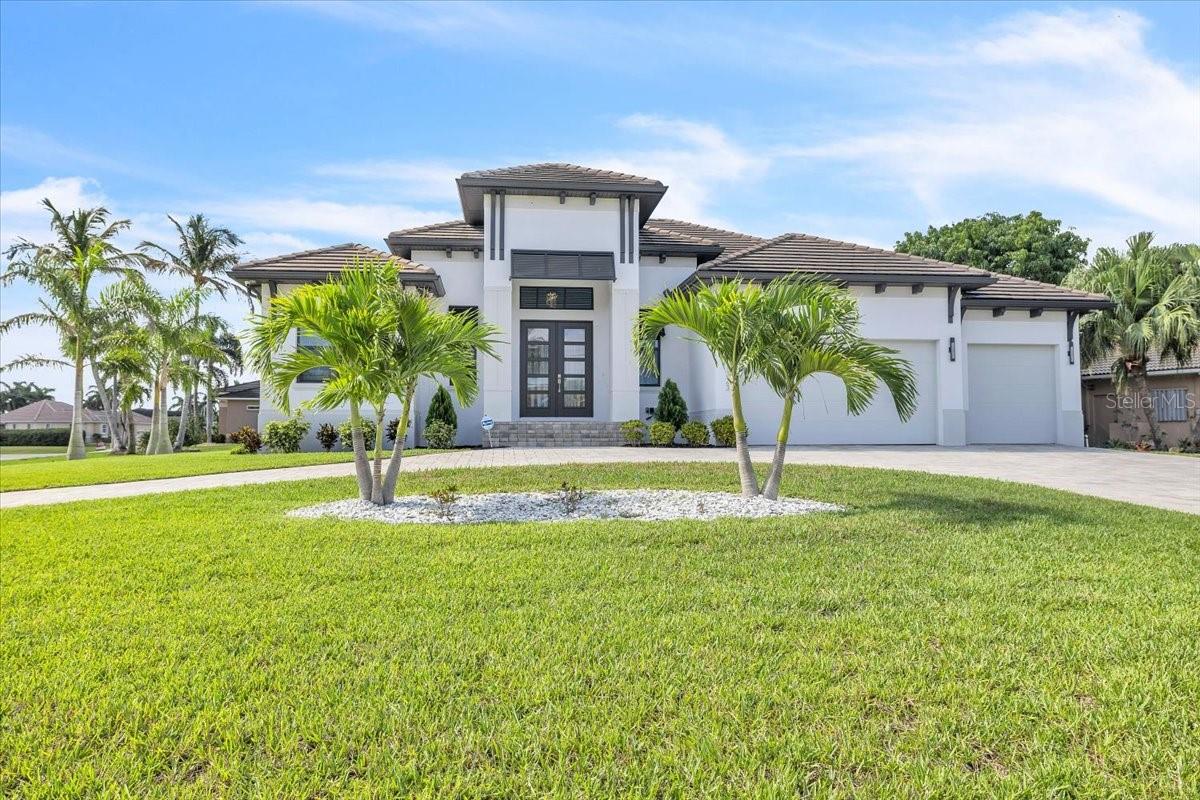 Built in 2022, this exceptional Harbor-built waterfront pool home is ideally positioned on a coveted corner lot in the highly sought-after “Bird Section” of Punta Gorda Isles. Thoughtfully elevated for added peace of mind and enhanced curb appeal, the residence offers 3 bedrooms plus a den, 3.5 baths, and 2,530 square feet of beautifully designed living space. A wide brick-paver circular driveway, expansive 675-square-foot three-car garage, and elegant double glass front doors create a striking first impression. The home’s refined coastal façade is complemented by lush tropical landscaping, swaying palms, stately columns, clean architectural lines, and a dramatic central entry tower. Impact windows & doors throughout. Boating enthusiasts will appreciate 40 feet of city-maintained concrete seawall and a private dock, with a scenic 10–15-minute ride through sailboat-access canals leading to the open waters of Charlotte Harbor and the Gulf—without fixed bridges. Inside, modern luxury meets thoughtful design. Soaring coffered ceilings adorned with 7¼-inch crown molding, stunning 24-inch porcelain tile flooring, and a spacious open-concept layout create a seamless blend of elegance and comfort. Natural light floods the interior, effortlessly connecting the great room, dining area, and kitchen—perfect for both everyday living and entertaining. Expansive 9’8” retractable sliders open to the lanai and resort-style pool area, creating a true indoor-outdoor living experience. The designer kitchen is both stylish and functional, featuring sleek white shaker cabinetry accented by brushed gold hardware, expansive quartz countertops, and high-end GE Profile stainless steel appliances—including a built-in double oven, French door refrigerator, and professional-style range hood. A statement island with contrasting cabinetry provides additional seating, storage, and a spacious undermount sink. A large walk-in pantry offers abundant storage and organization. Pendant lighting and subtle under-cabinet illumination enhance the warm, inviting atmosphere, while large windows and sliding glass doors frame serene water views. Designed for comfort and privacy, all three bedrooms feature en-suite baths. The owner’s suite serves as a private retreat, showcasing a tray ceiling and sliding glass doors that open directly to the pool. Double doors lead to a spa-inspired bath centered around a freestanding soaking tub, complemented by dual vanities, a frameless glass Roman shower with dual shower heads—including a rain shower—and a private water closet. Spacious walk-in closets offer exceptional storage.
Step outside to your private oasis, where a generously sized covered lanai with ceiling fans ensures year-round enjoyment. The brick-paver lanai and pool deck include an outdoor kitchen, perfect for entertaining. Beyond, a heated PebbleTec pool and spa take center stage, enhanced by a tranquil waterfall and relaxing sun shelf. A large panoramic screened enclosure provides unobstructed views and a seamless connection to the waterfront setting. Additional highlights include a versatile den with a half bath, a well-appointed laundry room with an adjoining mudroom area, and numerous upscale features throughout—truly offering the best of Florida waterfront living.
**PLEASE ENJOY THE 3D INTERACTIVE VIRTUAL TOUR ASSOCIATED WITH THIS LISTING**
