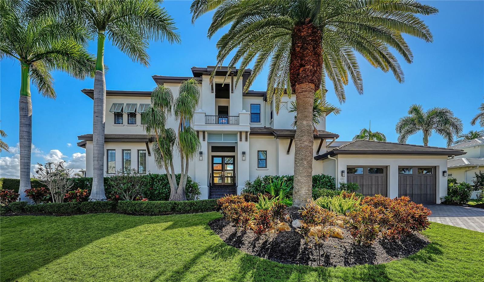 590 Birdie Lane is the definition of "having it all" - private, waterfront luxury with bay and beach access - just minutes from vibrant St. Armand's Circle and downtown Sarasota's dining and cultural scene.  It's coastal elegance at its best - refined custom interiors and effortless indoor-outdoor living. Perfectly positioned on a rare Longboat Key homesite — one home from open bay — capturing sweeping water views while offering peace of mind and protection that comes with ideal placement and newer construction. Built by John Cannon in 2017, this West Indies–inspired home in desirable Country Club Shores spans nearly 4,300 sf with four bedrooms, four and a half baths, a private office, gameroom and multiple outdoor living spaces. From the moment you enter, there's a feel of sophistication and craftsmanship - evident in the volume and coffered ceilings, extensive wainscoting, quartz-surround fireplace with custom built-ins and expansive walls of 10-foot pocketing sliders that open to turquoise water views. The kitchen is both a statement and a centerpiece - featuring Sub-Zero and Wolf appliances, quartz countertops, an oversized island, and a hidden walk-in pantry. A custom wine bar with Sub-Zero refrigeration enhances the home’s entertaining appeal. The primary suite is a private retreat with access to the pool, tray ceiling and dual custom walk-in closets.  The spa-inspired bath showcases a walk-in tiled shower, dual vanities, mother-of-pearl accents and a central soaking tub. The home is designed for privacy for family and guests - with additional upstairs bedrooms offering en-suite baths and generous closets. Outdoor living is equally extraordinary. Coral stone decks, custom wood ceilings on covered patios, and lush tropical landscaping frame the PebbleTec pool with infinity-edge spa, sun ledge and built-in loungers. The designer outdoor kitchen includes grill, sink, and refrigeration - creating a seamless setting for waterfront entertaining.  For boating enthusiasts, the deep-water canal frontage includes a composite dock, 16,000-lb lift, kayak launch, and newer seawall  — providing immediate access to Sarasota Bay and minutes to the open Gulf.  Blending modern resilience with convenience, this home offers an elevator, impact glass windows and doors throughout, 14ft elevation, a generator, tankless water heaters, electronic shades and an air-conditioned garage.  This is a rare opportunity to experience elevated coastal living on one of Longboat Key’s most desirable waterfront settings — where panoramic views, beach access and boating convenience converge in a beautifully executed custom residence.