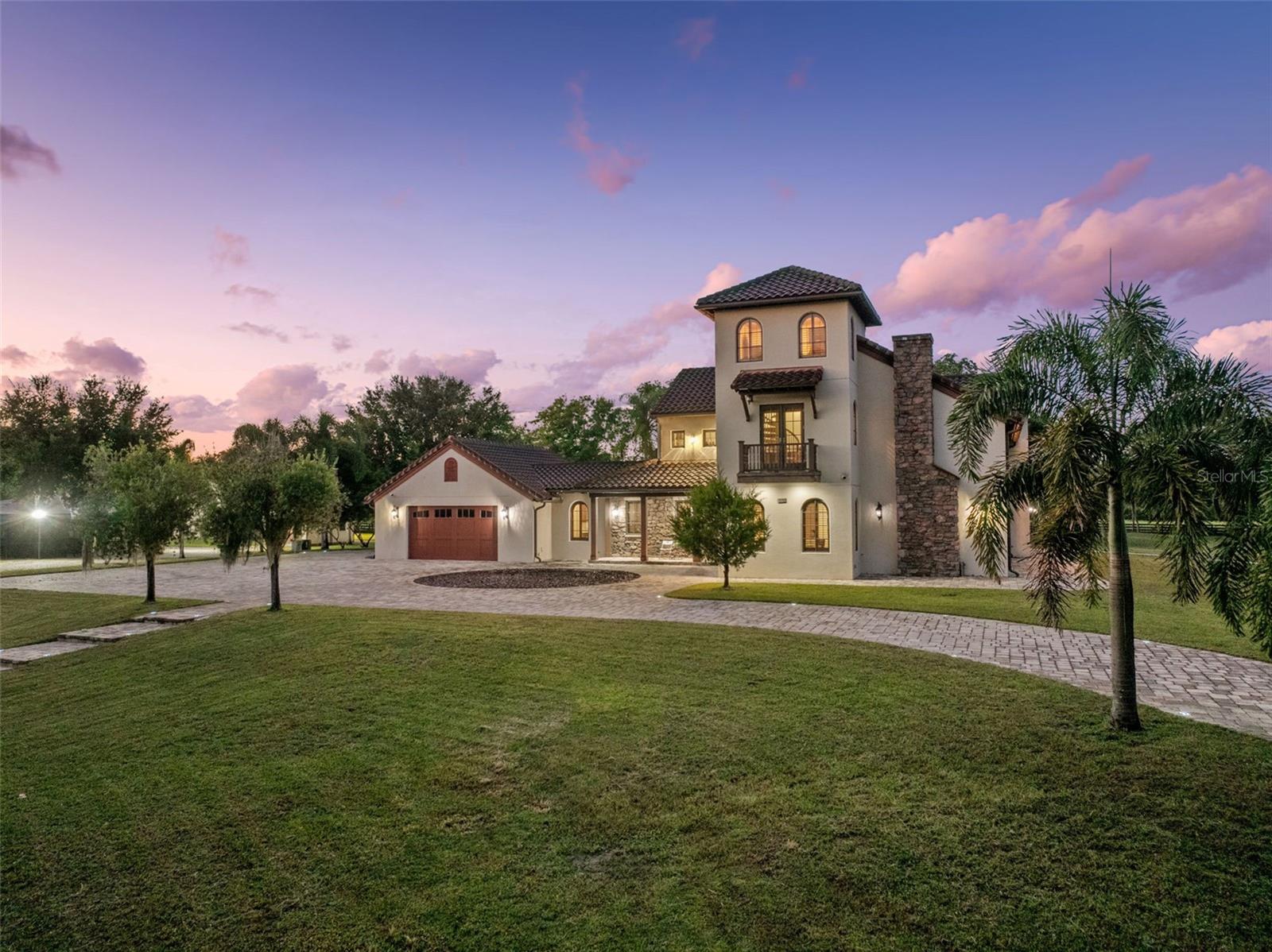 Welcome to 11205 Tindall Road – Experience the epitome of luxury living with this Lakefront Spanish Masterpiece by award-winning McNally Construction Group, perfectly set on a rare 10.42-acre gated estate in the heart of Lake Nona. Nestled along the serene southwest shore of Lake Hart, this one-of-a-kind property is among the largest remaining lakefront estates in the area—offering unmatched privacy, space, and security. A beautifully landscaped driveway leads to the home’s grand three-story façade, where panoramic lake views immediately capture your attention. Inside, the home exudes sophistication with a spacious living room, private office, and stunning glass-railed staircase. At the heart of the home, the chef’s kitchen, dining area, and great room impress with 20-foot vaulted ceilings, custom wood beams and tongue-and-groove detailing, and a breathtaking stone fireplace. A second-story glass balcony and floor-to-ceiling windows flood the space with natural light while framing endless lakefront vistas. The kitchen features custom cabinetry, dark granite countertops, and a large center island—perfect for entertaining. An elevator provides convenient access to the upper floors, where an expansive loft overlooks the great room. A spiral staircase leads to a third-floor bonus room/man cave with Dry Bar, offering the ideal space for relaxation or recreation. The residence features two luxurious master suites—one on each level—each with spa-inspired baths, walk-in closets, soaking tubs, and walk-in showers. Step outside to the screened lanai, complete with a summer kitchen and in-ground spa, creating the perfect setting for outdoor living. For water enthusiasts, the property includes a private dock with a boat lift, double jet ski lift, tile roof, and composite decking—ideal for days on the water. A 2,250 SF detached garage/workshop with bathrooms and dual 14’ roll-up doors offers ample storage for RVs, boats, and recreational vehicles. Other Notable Features- Fully Fenced, Fully Irrigated w/ (2) Wells, Entire Property covered by Closed Circuit Security System/Cameras, Multiple Gardens and more. This property is being Sold Fully Furnished with ALL Tractors, Boat and Equipment Included! Located just minutes from Medical City, Lake Nona Town Center, fine dining, shopping, and major highways, this estate offers the rare opportunity to enjoy secluded lakefront living without sacrificing convenience. Don’t miss this exceptional opportunity to own one of Lake Nona’s most extraordinary estates—schedule your private tour today.