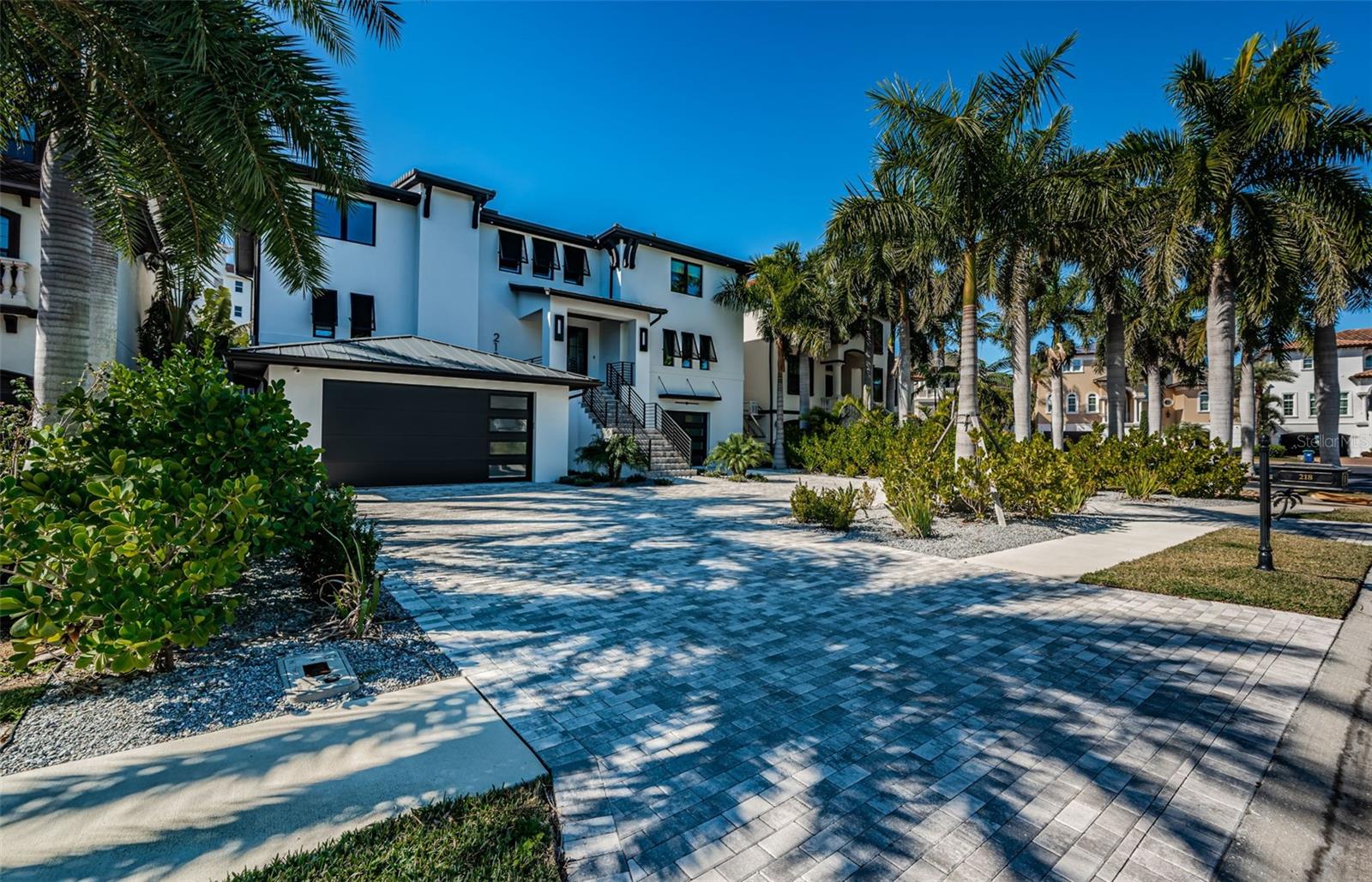 THE ESSENCE OF COASTAL ELEGANCE, REIMAGINED! Located across from the beach in the only gated boating and tennis community on the barrier islands of Tampa Bay, this gorgeous 5 bedroom, 5 ½ bath estate residence offers an impressive 9291 total sqft under roof. Built in 2023 with all block construction and richly-distinctive exterior appointments, you’ll love its clean contemporary lines and luxurious feel. A grand circular paver driveway and fine covered entry welcome you to a soaring 20ft-high foyer and an inspiring living space. Large-format porcelain floors, dazzling designer lighting, and expansive window views galore deliver a light, open and engaging appeal. This remarkable smart home boasts whole house automation of lighting, window treatments, climate control, audio and more. A brilliant great room plan features a custom gas fireplace and media wall, with superb beamed ceiling accents. The open-concept designer chef’s kitchen is beautiful in its appearance and a culinary delight in its use – with coastal white shaker-style cabinetry, thick quartz counters, Subzero/Wolf appliances, gas cooking, sizable walk-in pantry, huge island bar and serving center, and full-height Subzero wine chiller. The open/airy dining area overlooks the waterfront and transitions to a fabulous 41ft-wide 535sqft luxury balcony with built-in gas cooking center/kitchen. Balcony provides multiple seating areas and wonderful views of the pool deck/waterfront. The 1st level guest bedroom suite contains a sumptuous full bath and provides access to the balcony. You’ll appreciate the dedicated office with generous closet storage. Upstairs you’ll discover exquisite wood floors, three plush bedroom suites and a spacious family/media room with rich custom wetbar and access to the upper-level balcony. The owner’s suite is truly a joy with its posh morning bar/beverage center, two walk-in closet systems, recessed ceilings, and private access to the covered 410sqft upper-level luxury balcony – the perfect place to start and end your day. The owner’s bath is a lavish, pampering retreat - with custom his/her vanities, radiant quartz surfaces, dedicated sit-down cosmetics center, free-standing soaking tub, and a strikingly-attractive walk-in glass rainshower enclosure. All bedrooms are oversized and all baths are elegantly-finished. A custom built-in “mud room” leads to the massive garage area and the lower-level 520sqft covered deck overlooking the pool and waterfront. Stunning Pebbletec pool/spa (heated and with salt chlorination system) is encased in a splendid shellstone paver deck, ideal for lounging and entertaining. Adjacent to the waterfront, a lushly-landscaped synthetic grass seating area surrounds a modern gas firepit. This astonishing home includes a dual jet ski with rapid access to open water, a 3-stop luxe elevator, tankless hot water heating, backup power gas generator and so much more. A fantastic home in a outstanding private location just a short walk to the beach. Don’t miss this rare opportunity, homes located directly on boating water seldomly become available in the Redington Shores Yacht & Tennis Club. Measurements are estimates, buyer to verify.